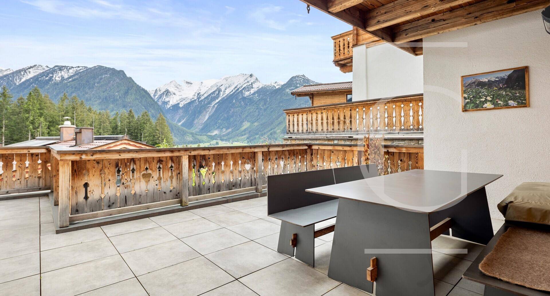 Große Terrasse mit modernen Sitzmöbeln und weitem Blick auf die Alpenlandschaft.