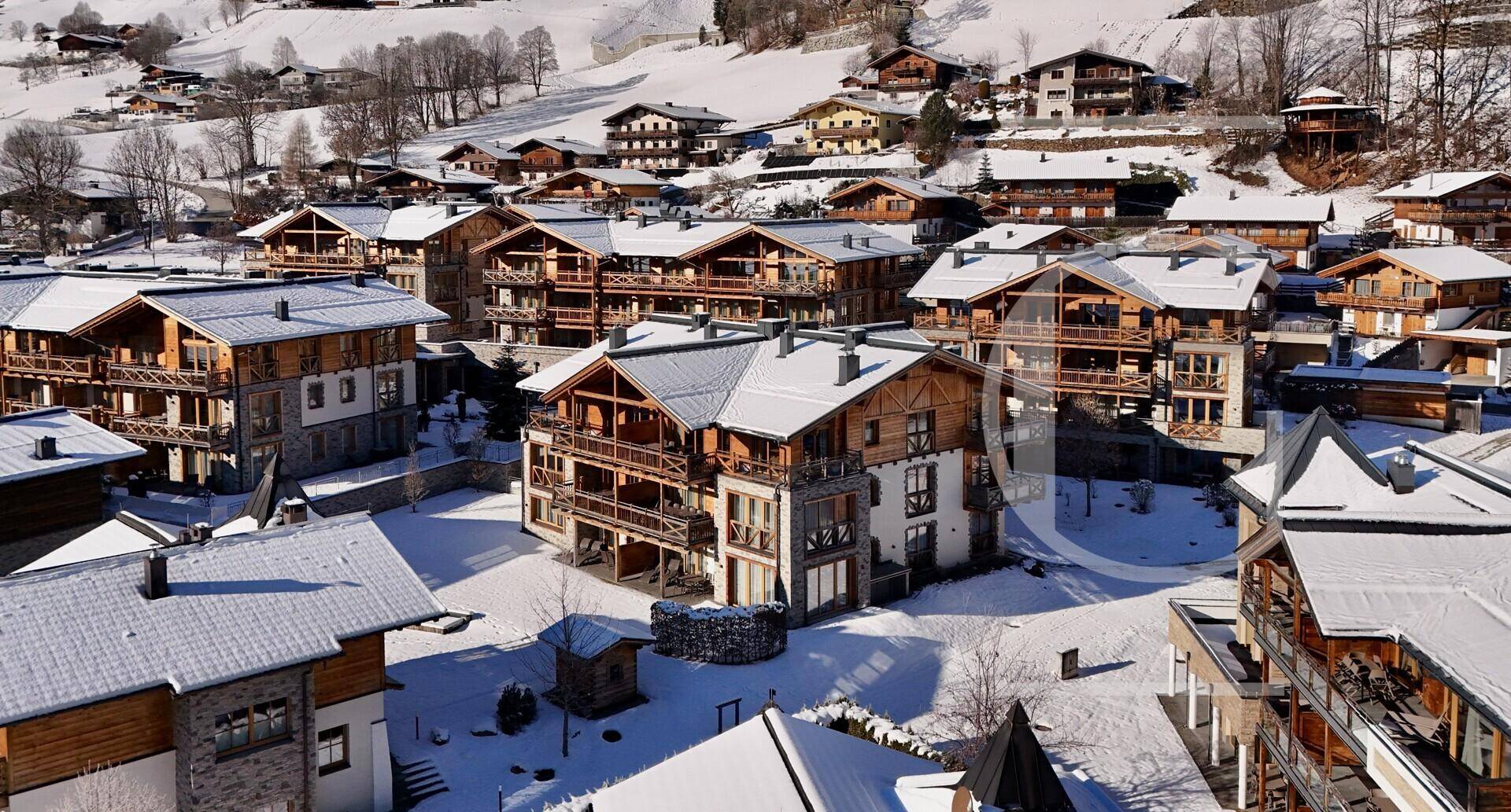 Panoramablick auf ein verschneites Bergdorf mit traditionellen Chalets und Winterlandschaft.