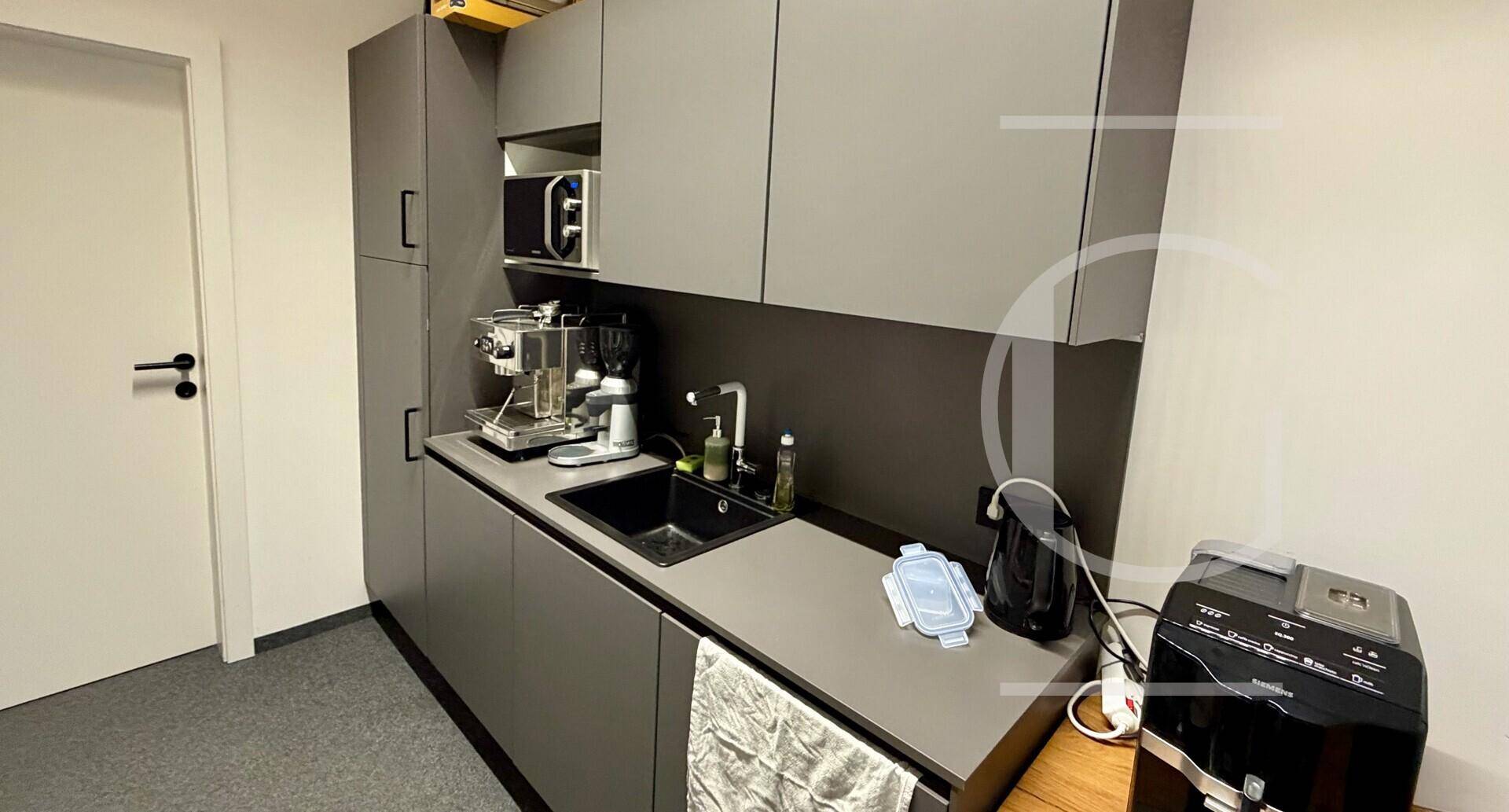 Moderne Teeküche mit grauen Schränken, Spüle und Kaffeemaschine für Mitarbeiter.