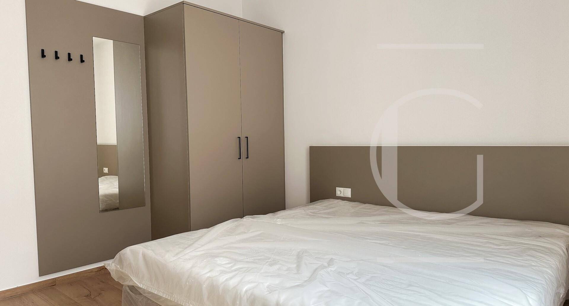Schlafzimmer mit Doppelbett, integriertem Kleiderschrank und Spiegel.