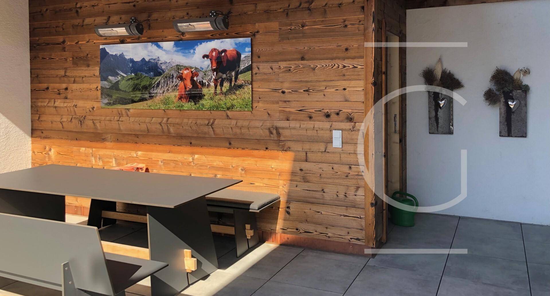 Überdachte Terrasse mit Holzwand, Sitzgelegenheiten und Heizstrahlern für kühle Abende.