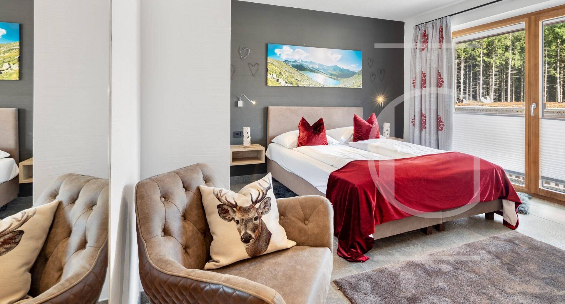 Modernes Schlafzimmer mit Doppelbett, dunklen Wänden und Blick ins Grüne durch das Fenster.