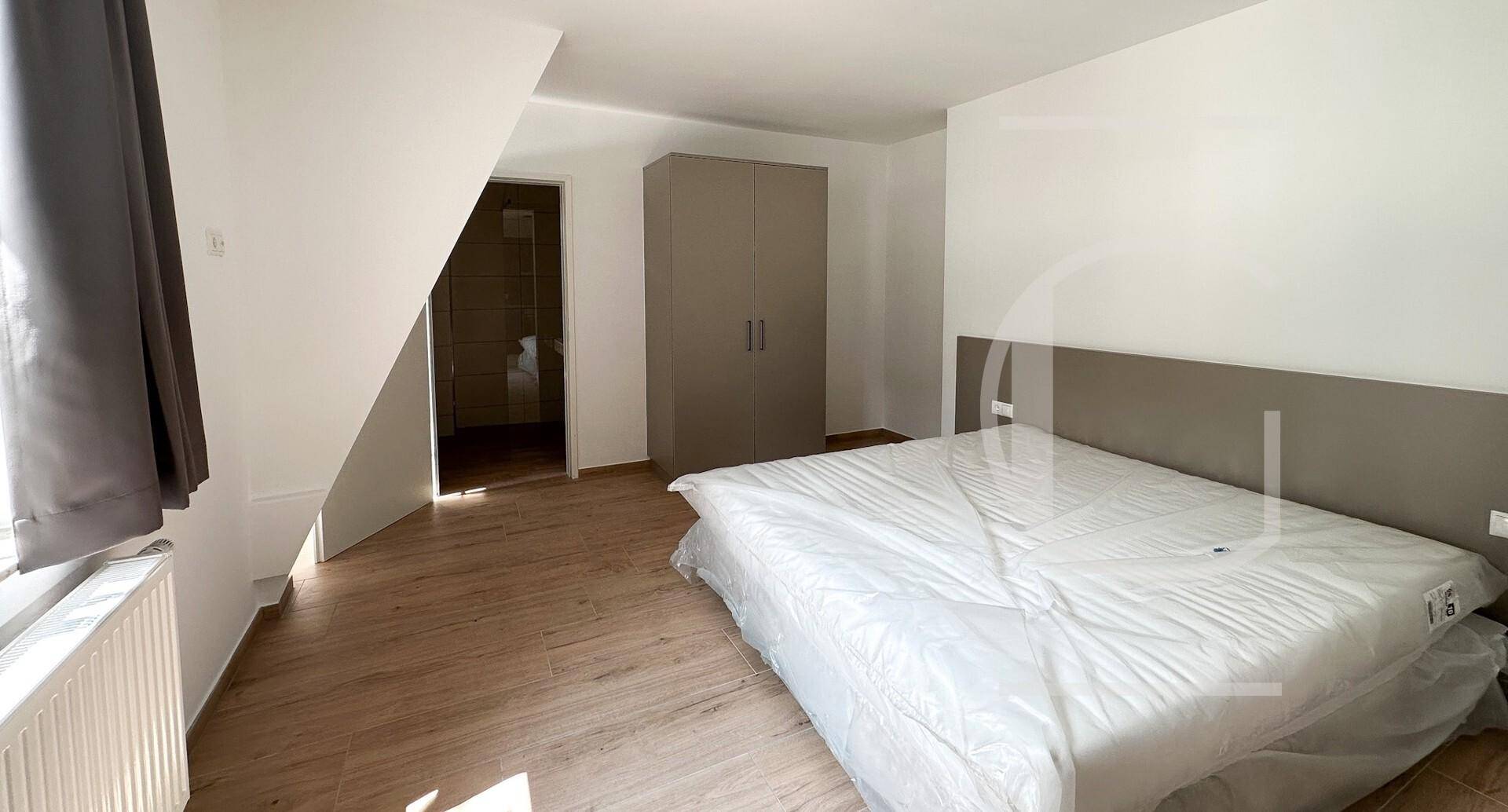 Helles Schlafzimmer mit Dachschräge, Laminatboden und einem Kleiderschrank.