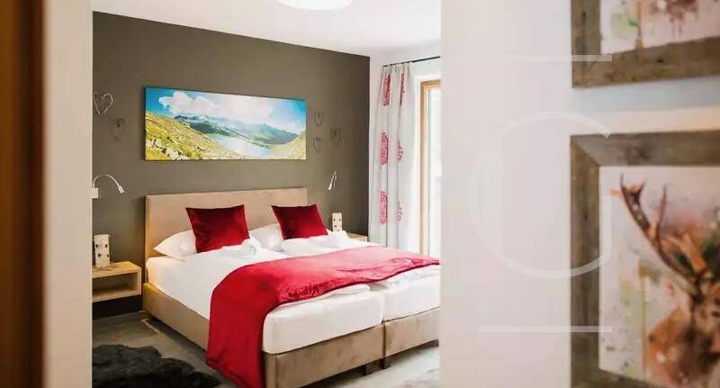 Helles Schlafzimmer mit Doppelbett, Holzboden und Wanddekoration im alpinen Stil.