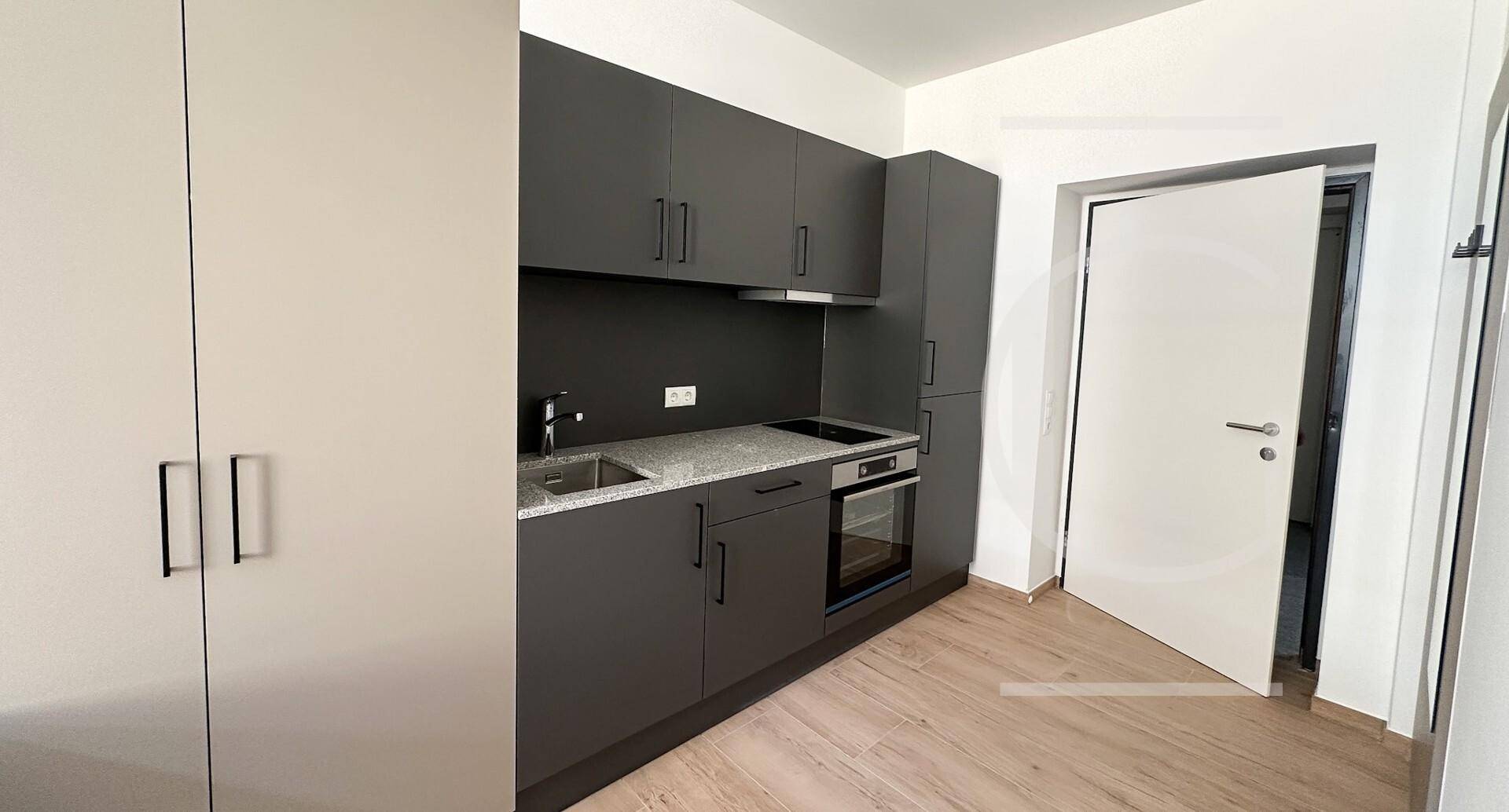 Moderne Küchenzeile in Grau mit integrierten Geräten und hellem Laminatboden.