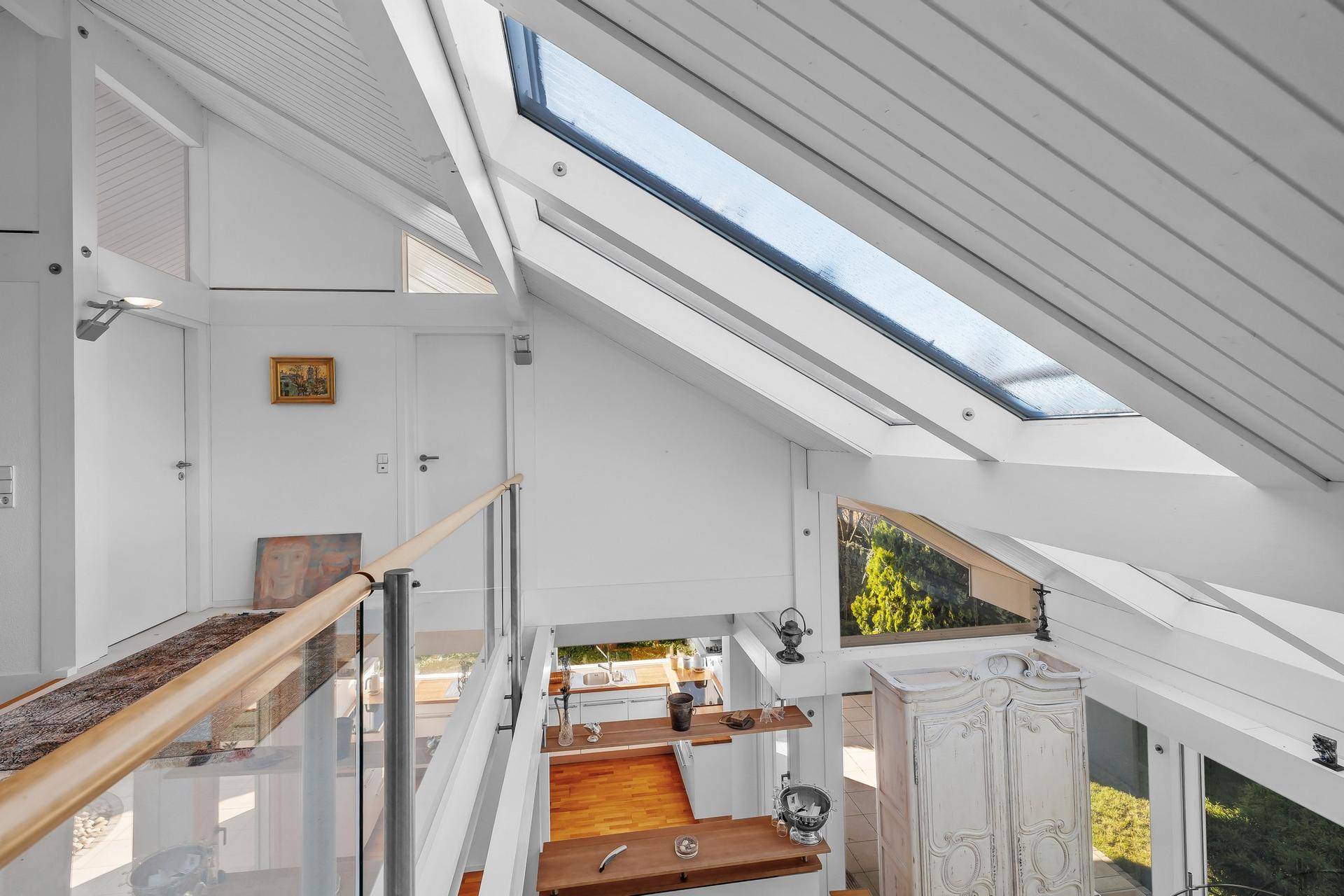 Blick von der Galerie auf den Essbereich und die Küche, mit hohen Decken und Dachfenstern.