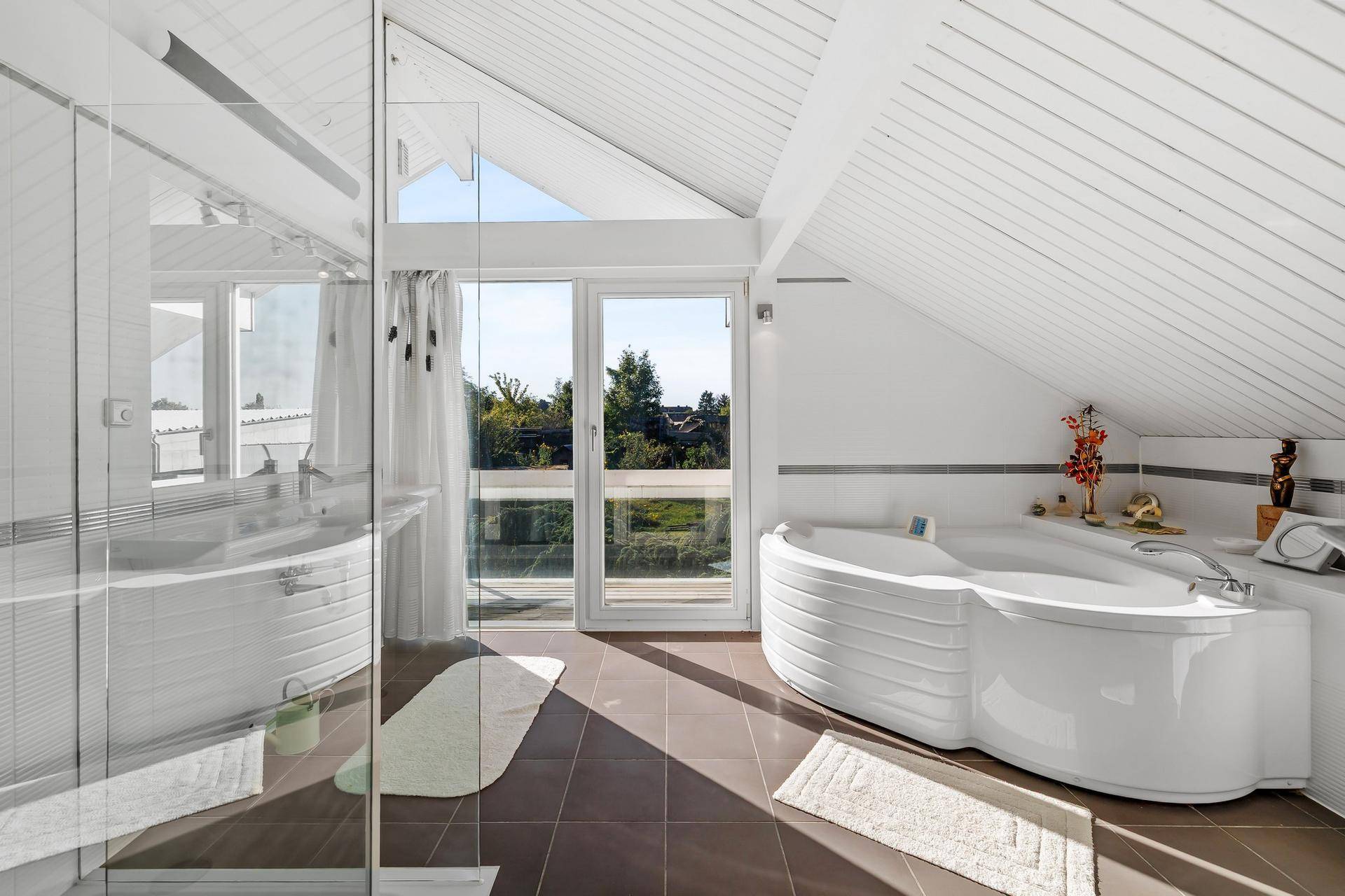 Modernes Badezimmer mit großer Eckbadewanne, Dusche und Zugang zu einem Balkon oder Terrasse.