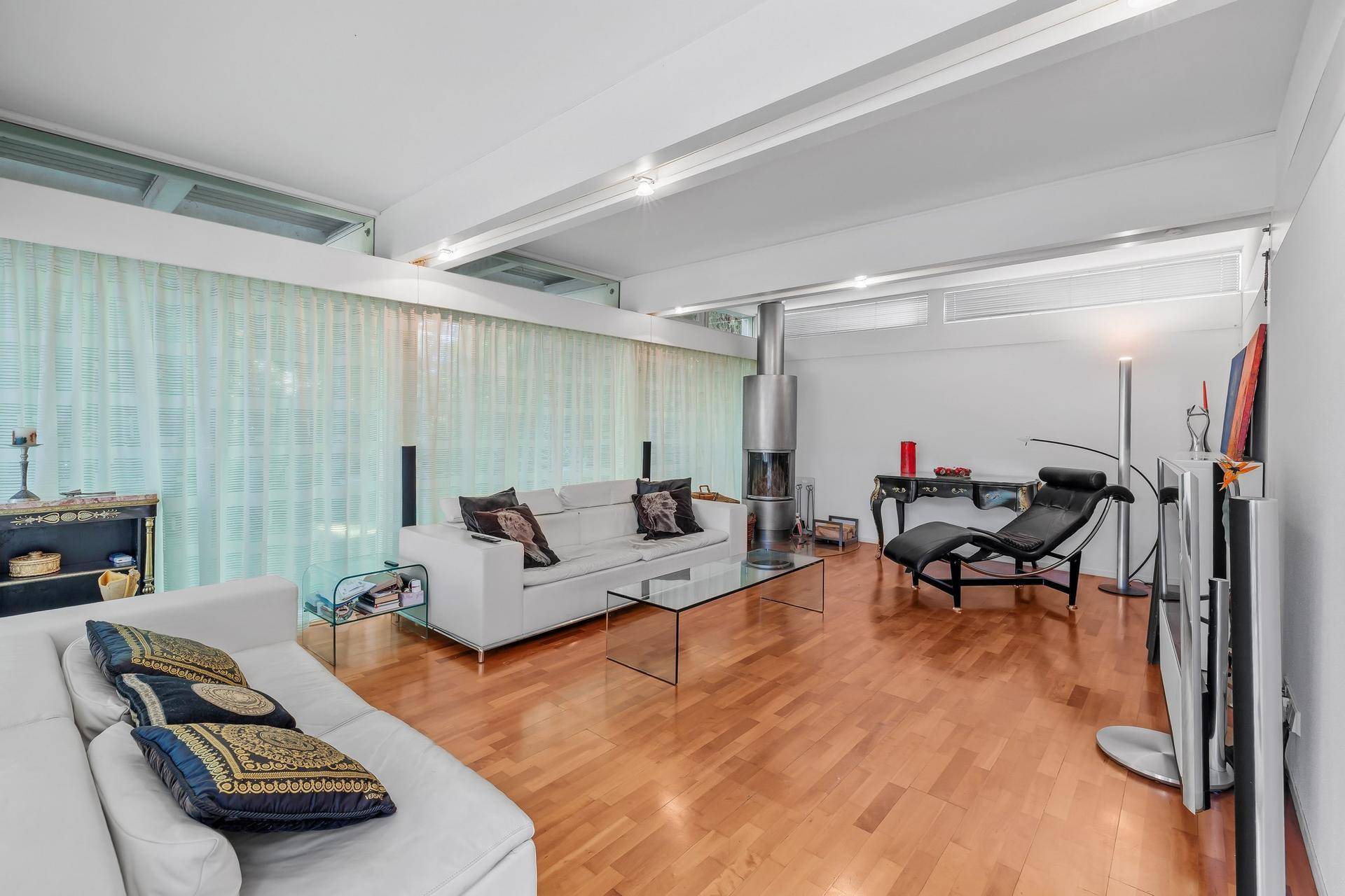 Geräumiges Wohnzimmer mit modernem Kamin, hellen Sofas und Holzboden, viel Tageslicht.