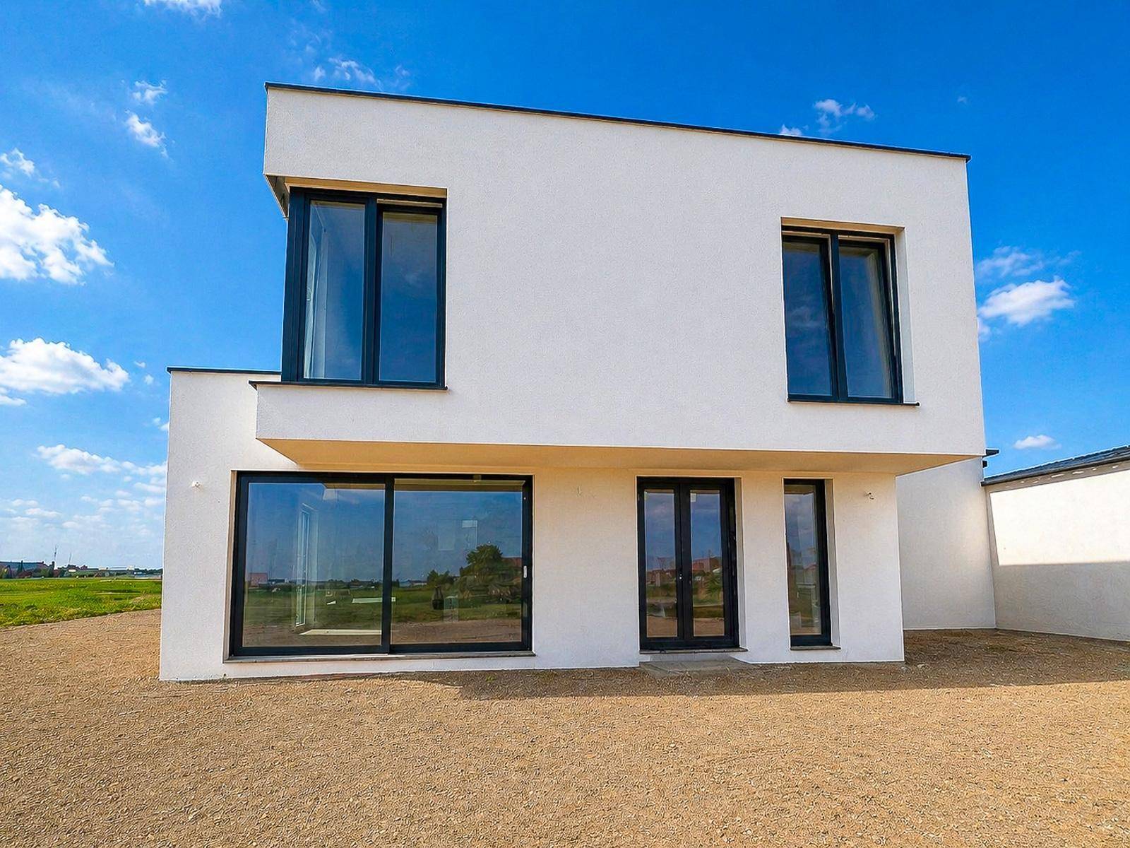 Nahaufnahme der modernen Fassade des Neubaus mit großen Fenstern und klaren Linien.
