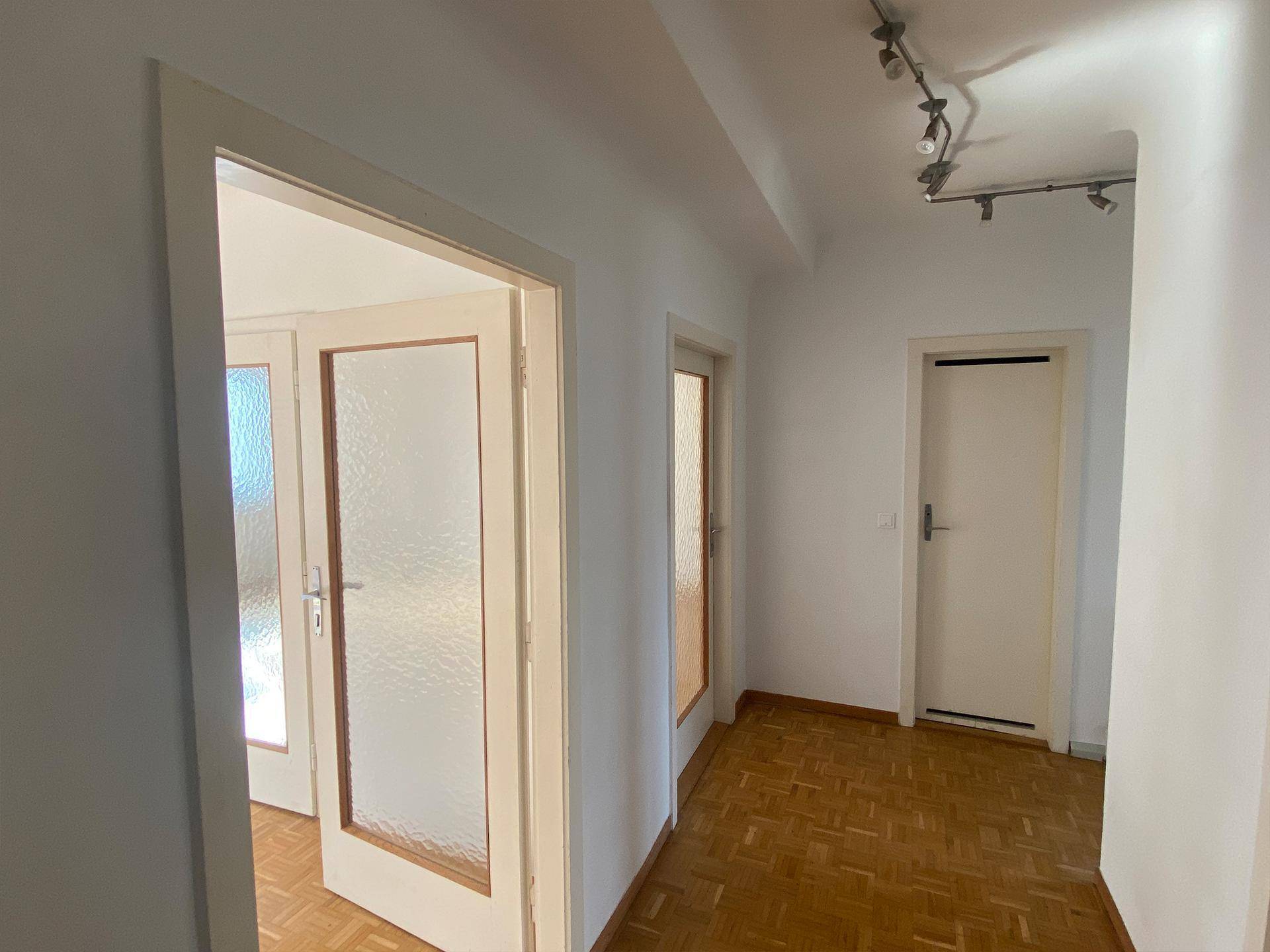Heller Flur mit Parkettboden und Türen zu verschiedenen Räumen.