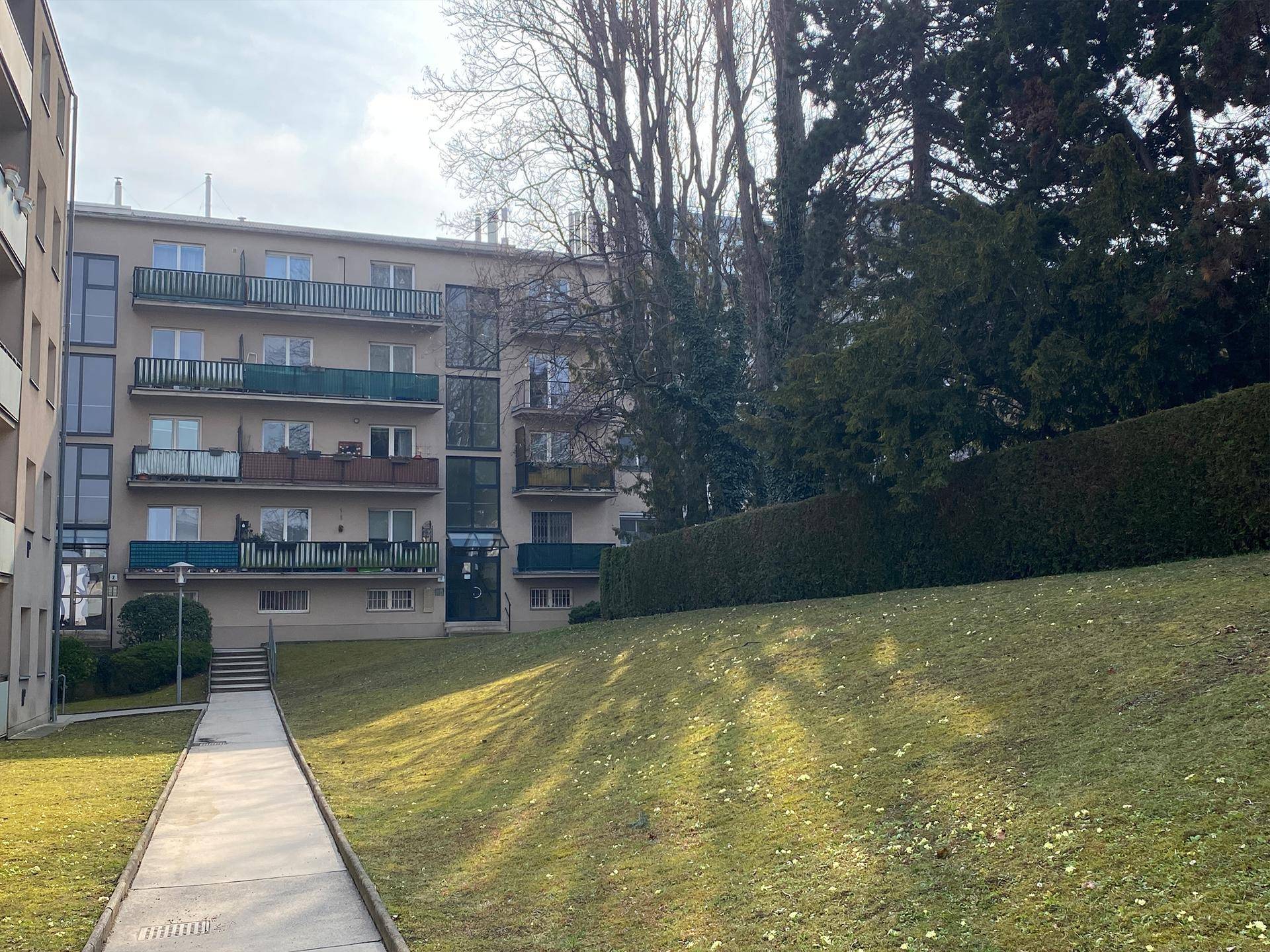 Mehrfamilienhaus mit Balkonen und einer grünen Rasenfläche im Vordergrund.