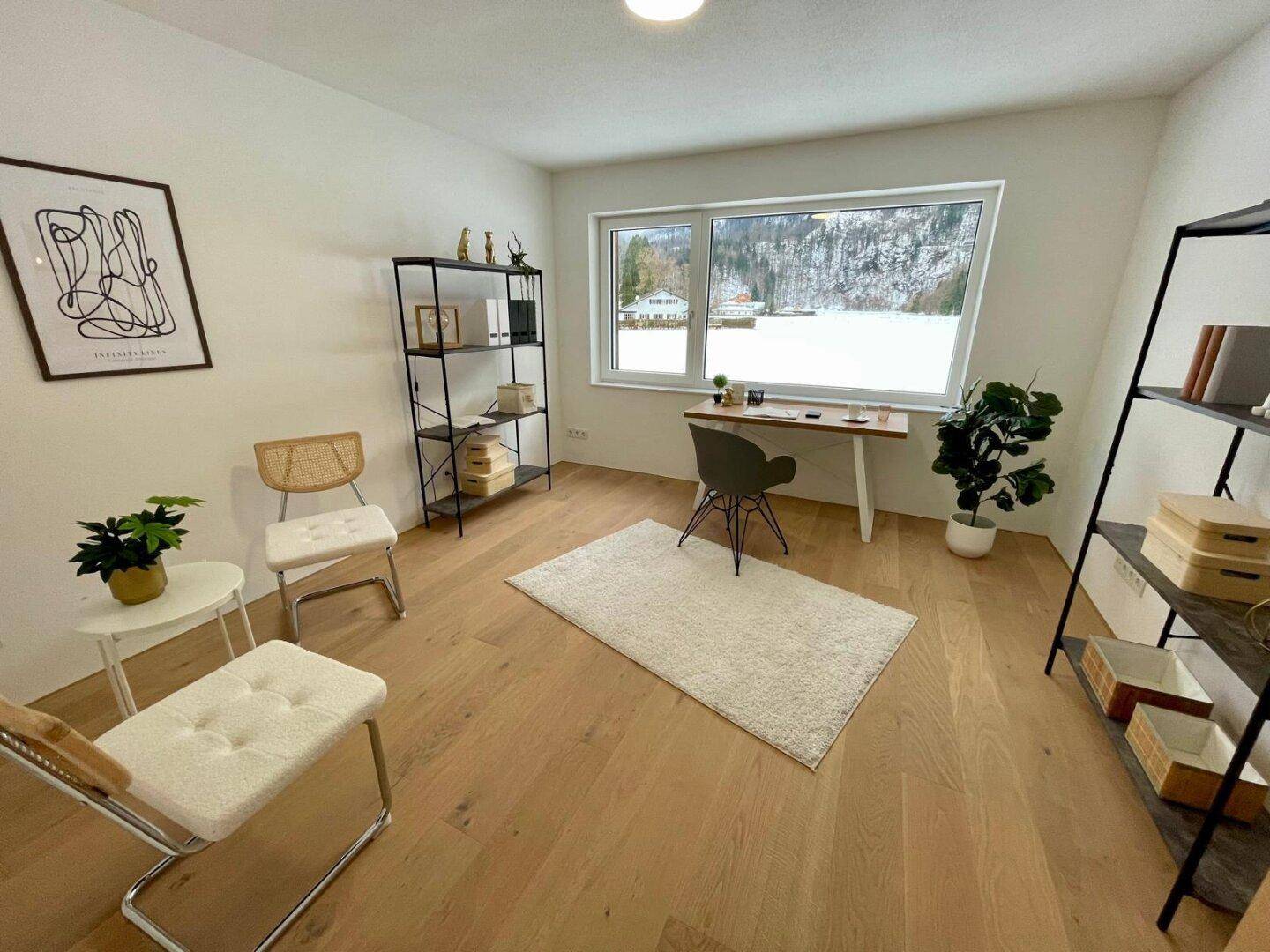 Helles Arbeitszimmer mit Holzboden, großem Fenster und Blick auf eine verschneite Landschaft.