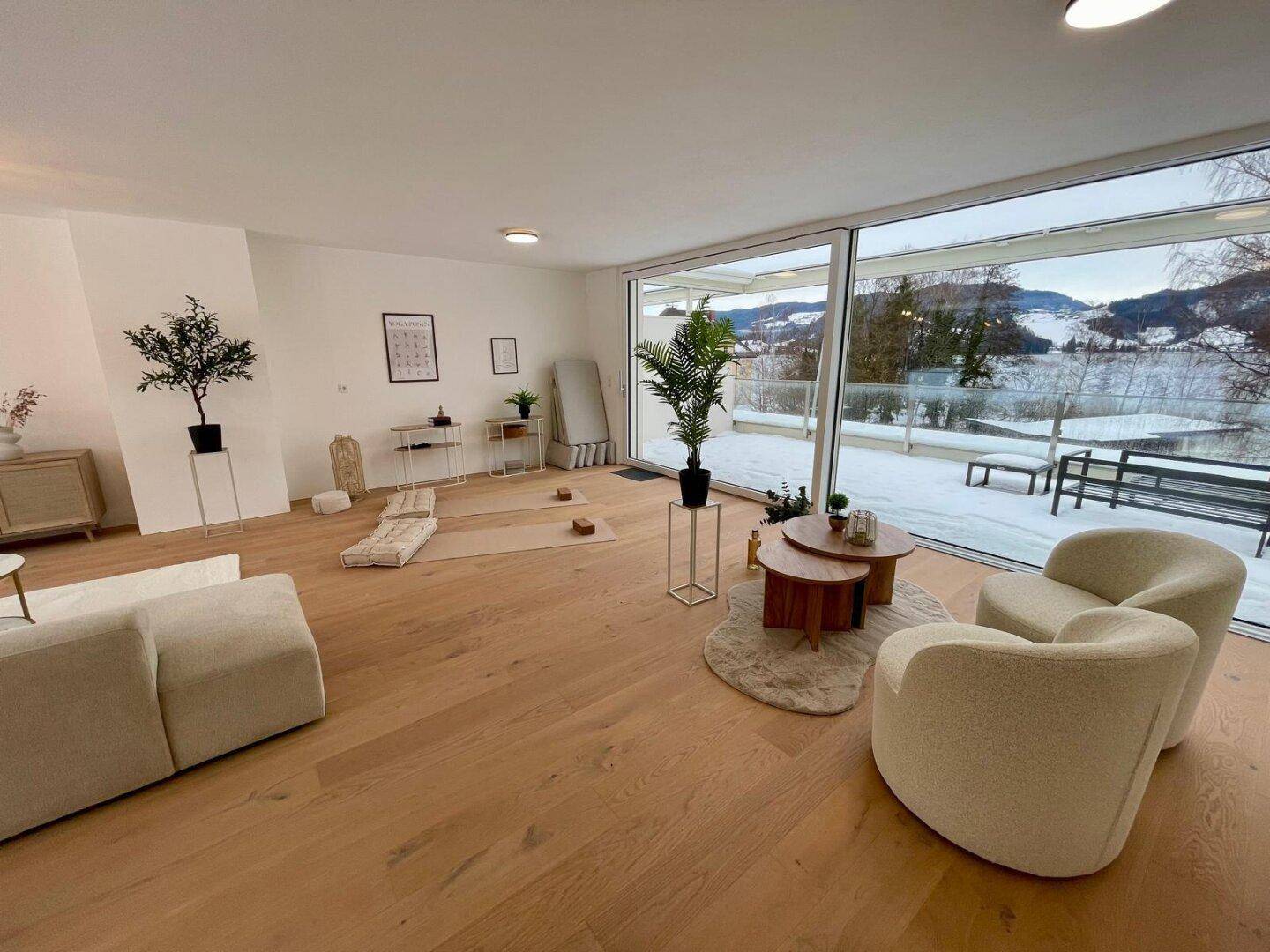 Geräumiger Wohnbereich mit großen Glasfronten, Holzboden und weitem Blick auf die verschneite Landschaft.