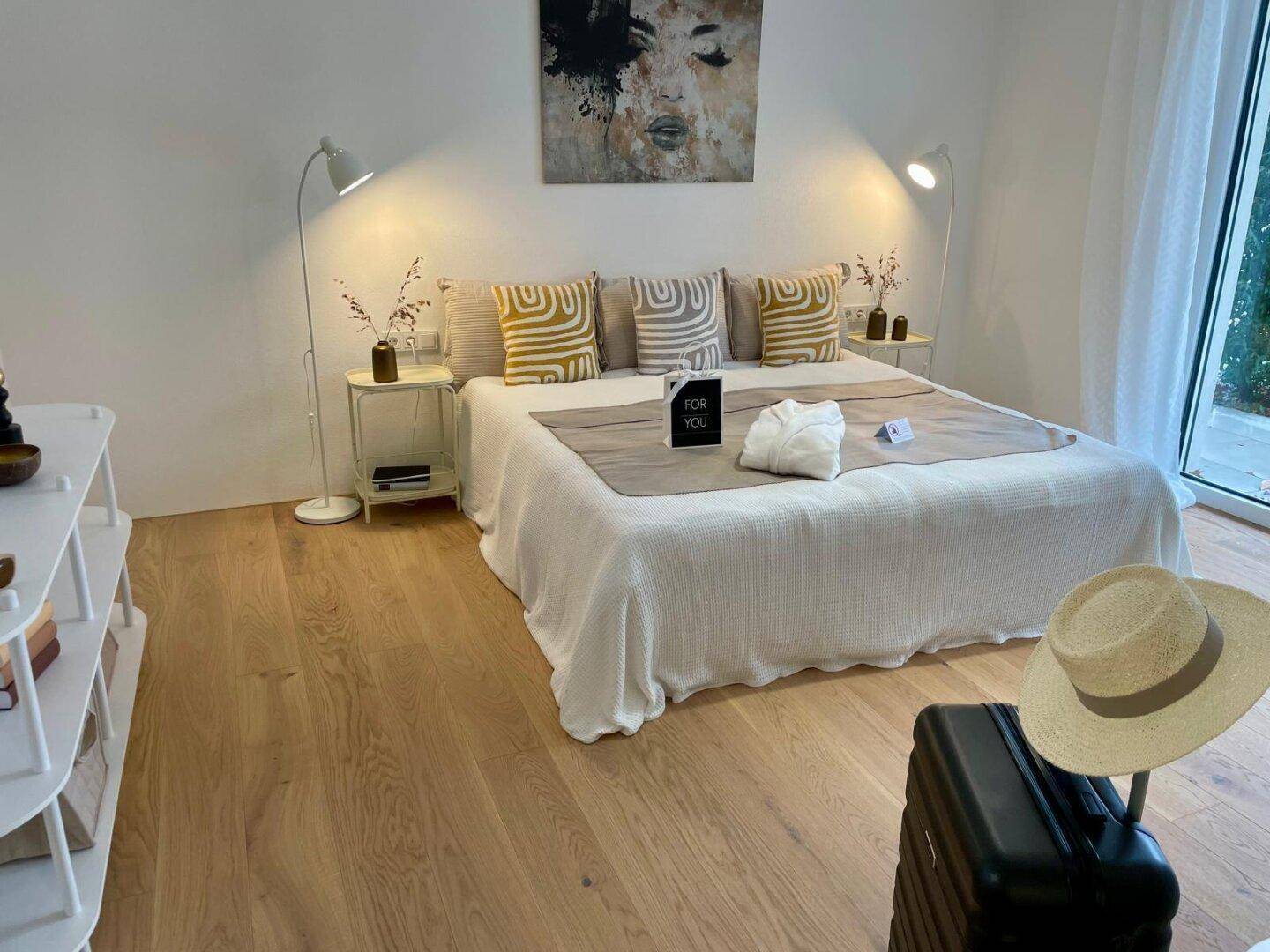 Gemütliches Schlafzimmer mit Holzboden, großem Bett und Zugang zu einem Außenbereich.
