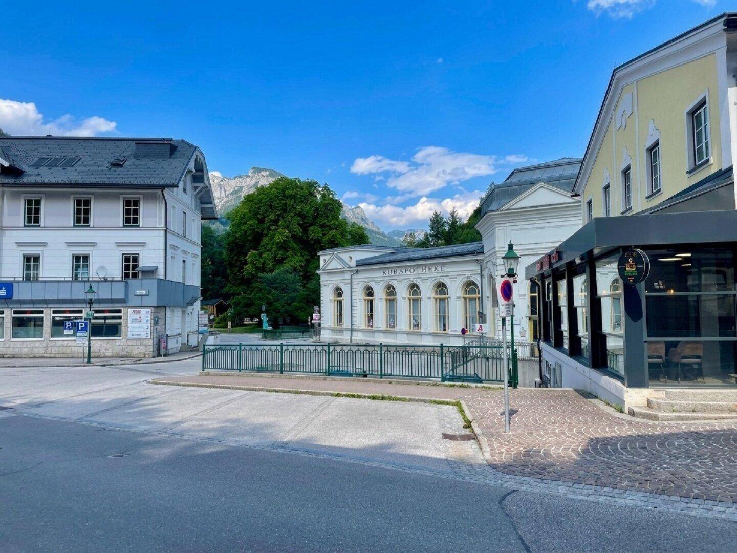Eine ruhige Straße in einer Stadt mit traditionellen Gebäuden und Bergen im Hintergrund.