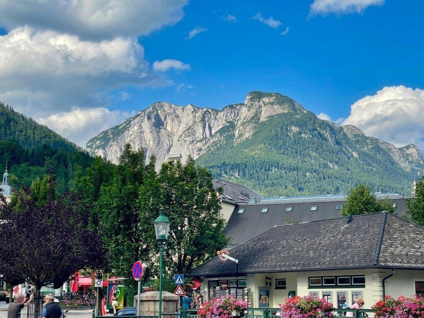 Majestätische Berglandschaft über den Dächern einer malerischen Stadt unter blauem Himmel.