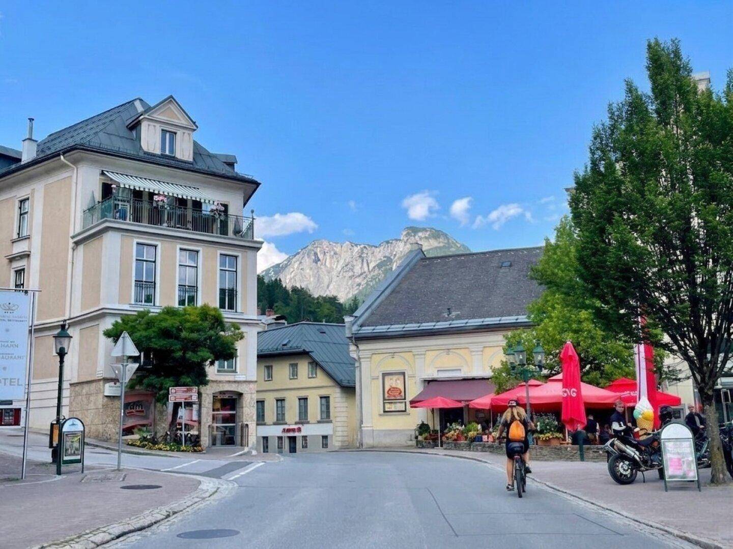 Eine charmante Straße mit historischen Gebäuden, Geschäften und einem beeindruckenden Bergblick.
