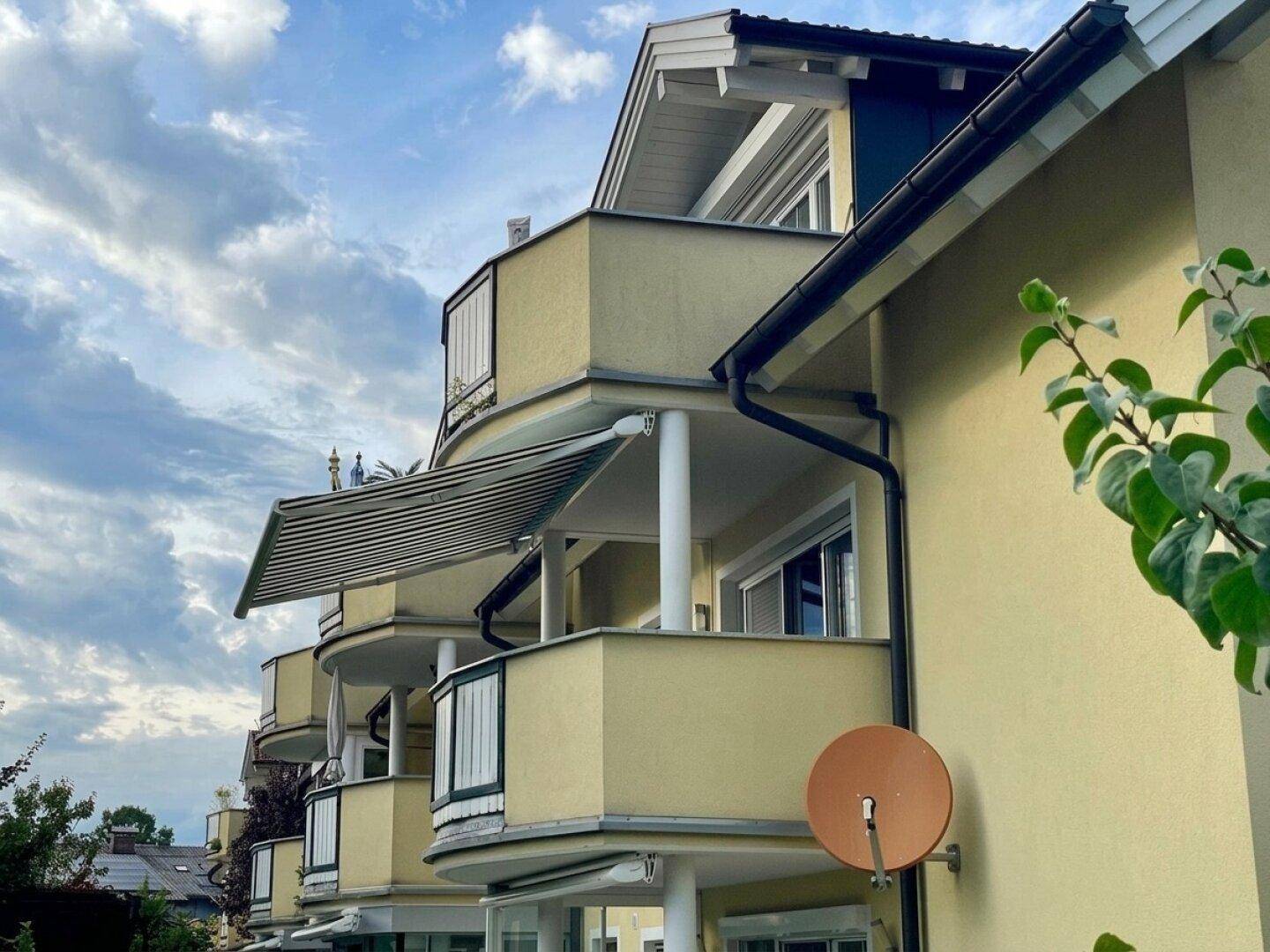 Seitenansicht des Gebäudes mit mehreren Balkonen und ausfahrbaren Markisen.