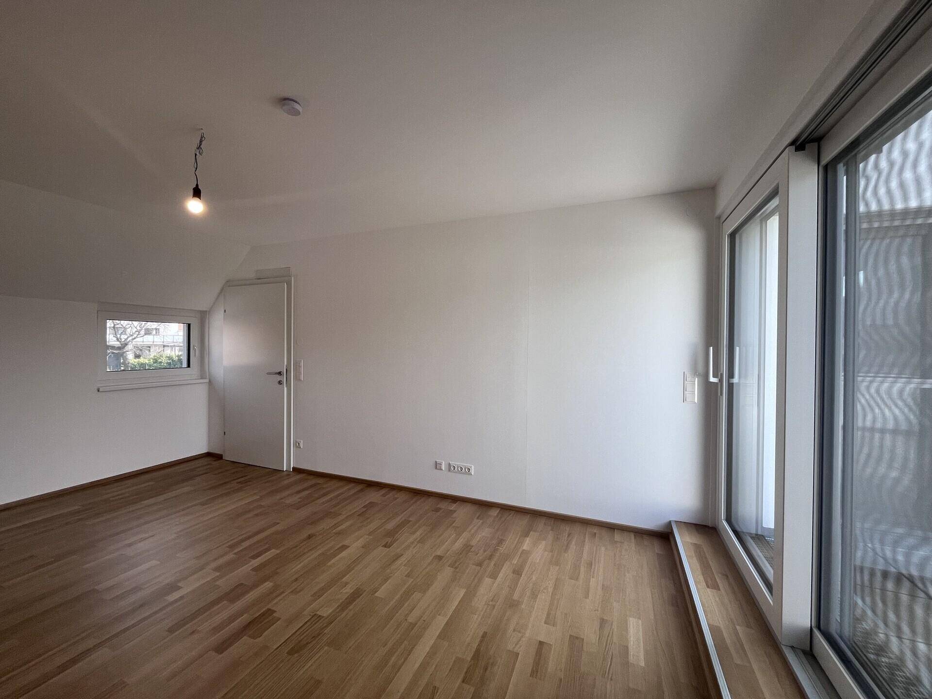 Geräumiges Schlafzimmer mit Parkettboden und Fenster, das viel Licht spendet.