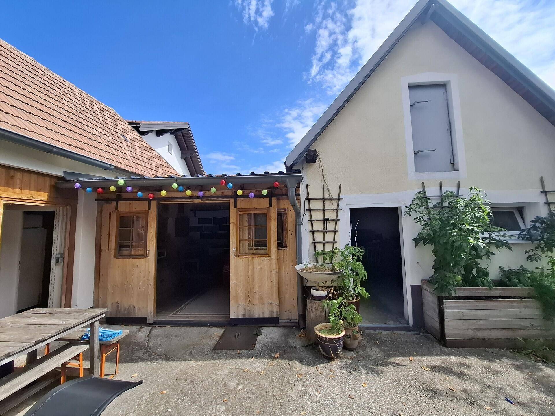 Detailansicht des Innenhofs mit offener Holzstruktur, bunten Lichterketten und rustikalem Holztisch.