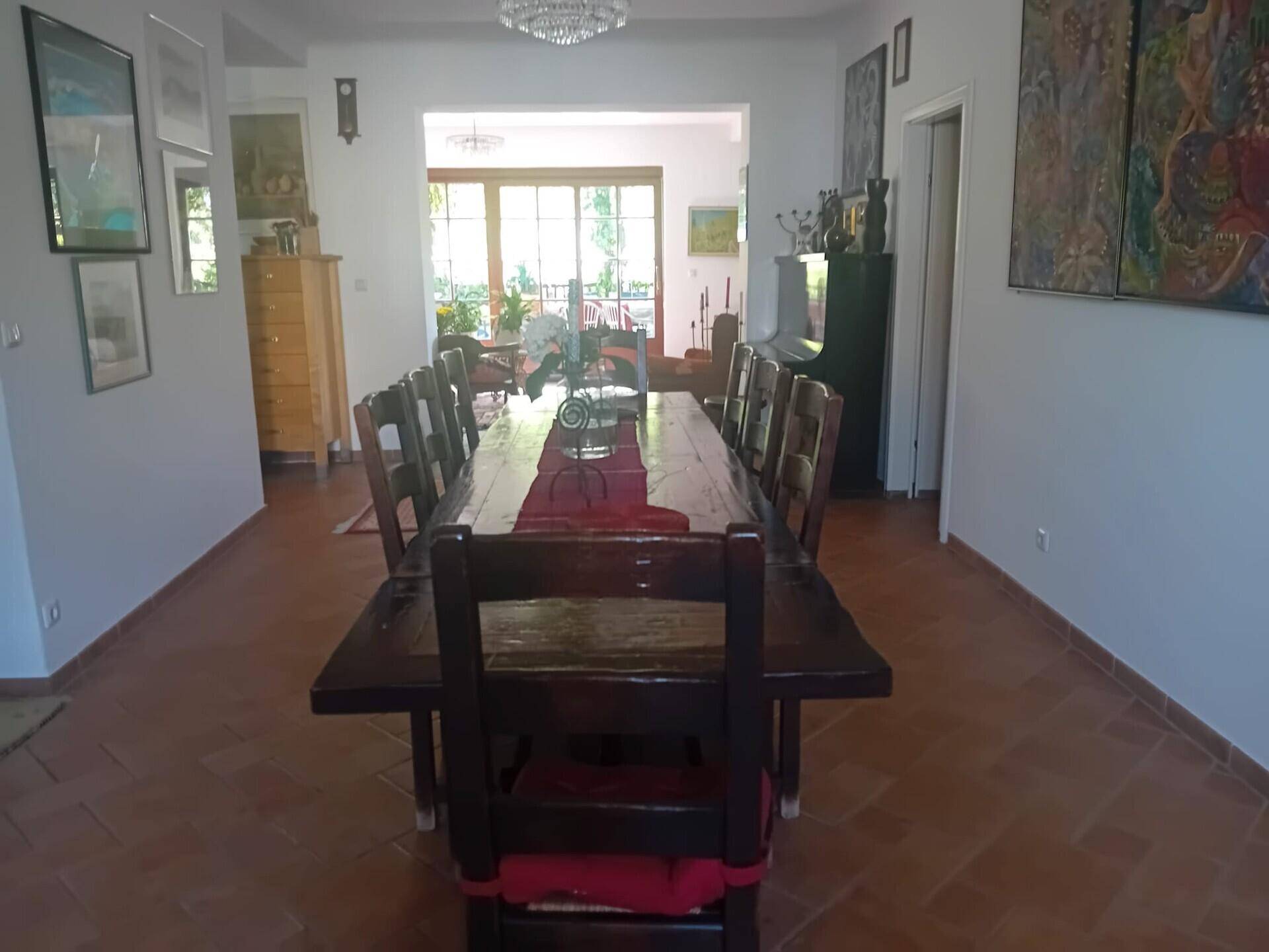 Geräumiges Esszimmer mit langem Holztisch, Terrakottaboden und Blick in den Gartenbereich.