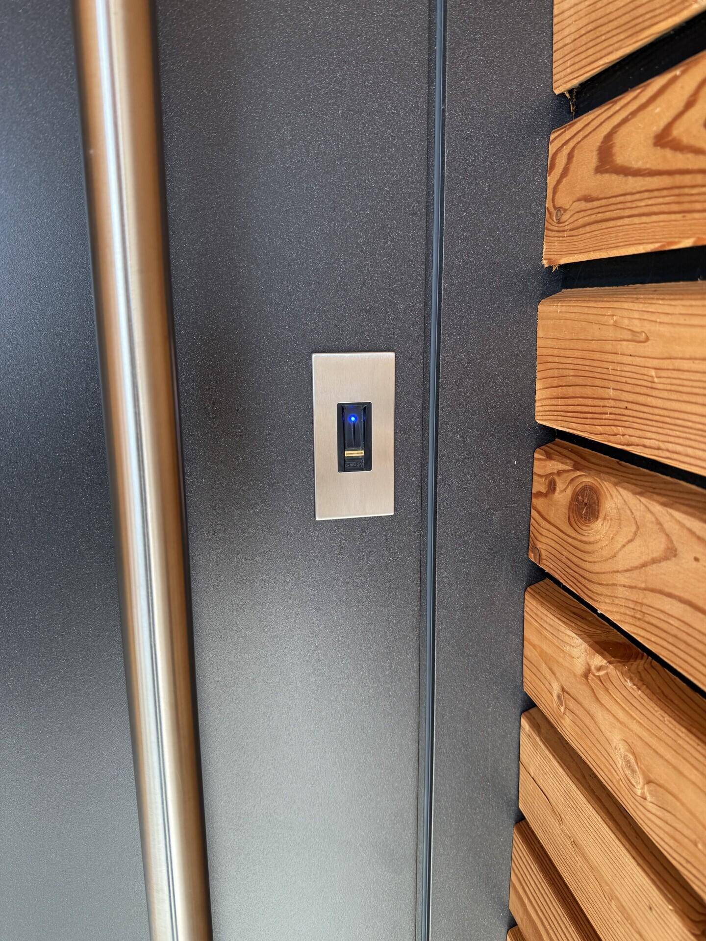 Detailaufnahme eines modernen Lichtschalters an einer Wand mit Holzverkleidung.
