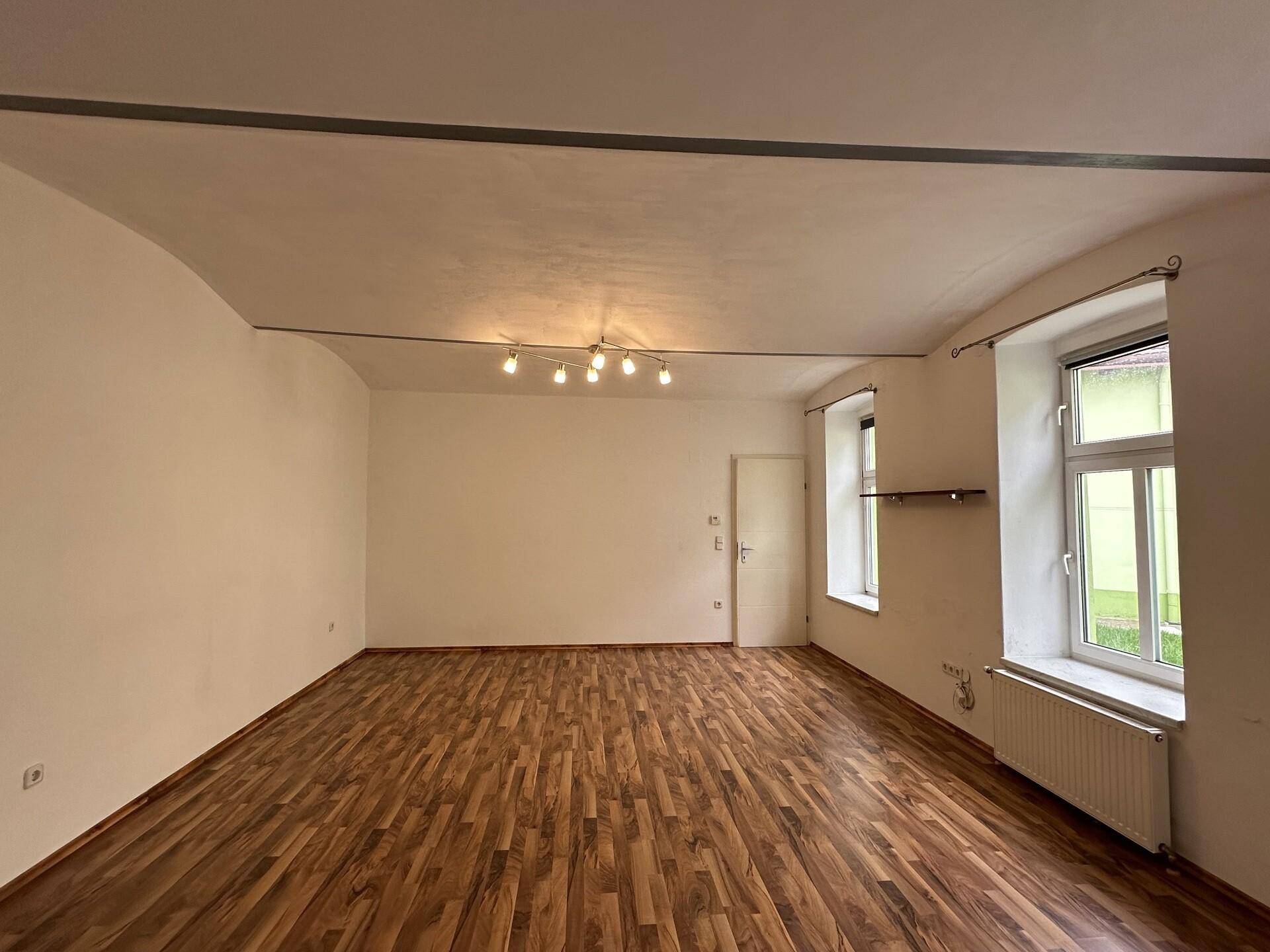 Heller Raum mit Holzboden und weiß gestrichenen Wänden, bereit zur Einrichtung.