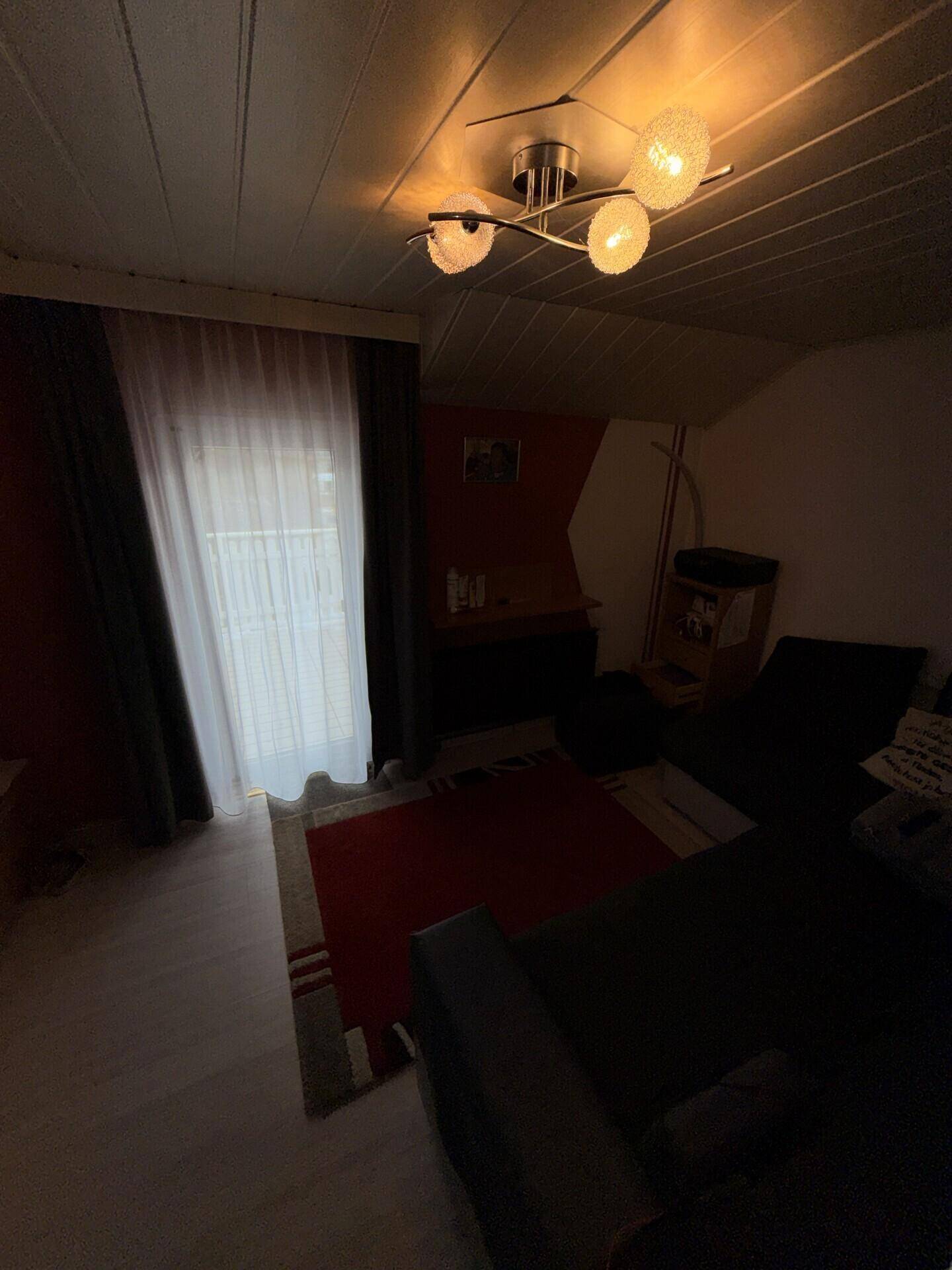 Dachgeschoss-Wohnzimmer mit Dachschrägen, Holzverkleidung und Sofa in gemütlichem Stil.