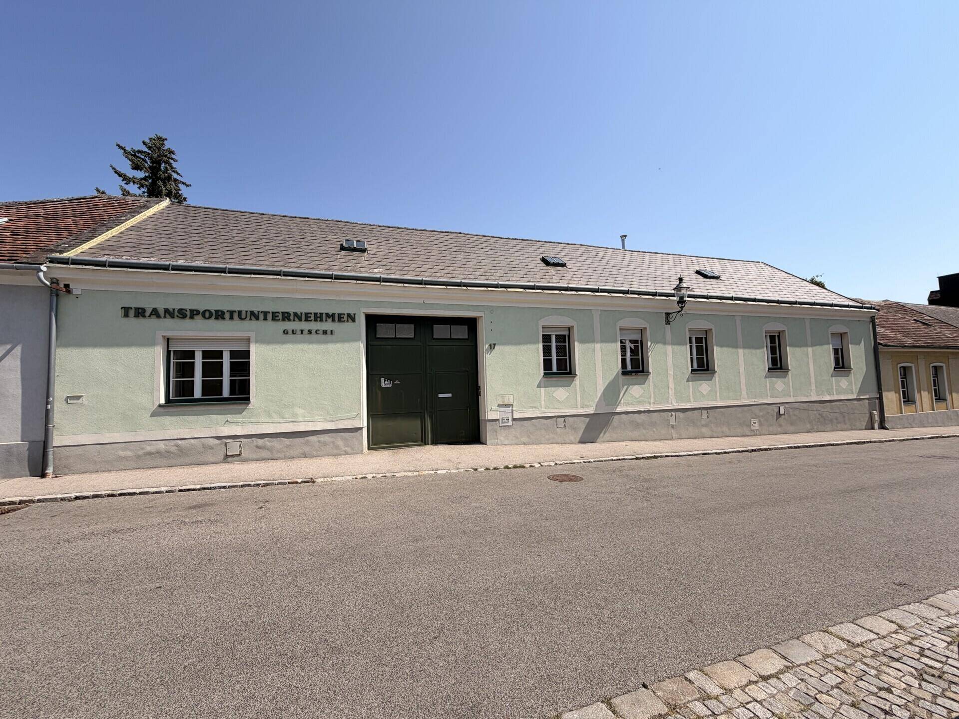 Fassade eines Gebäudes mit großem Garagentor und Beschriftung an der Straßenseite.