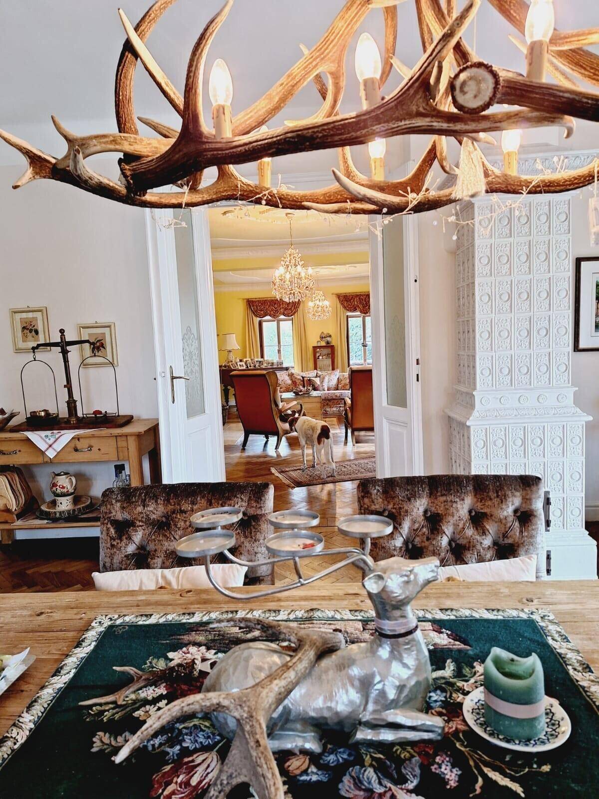Traditioneller Essbereich mit Hirschgeweih-Kronleuchter und Blick ins Wohnzimmer.