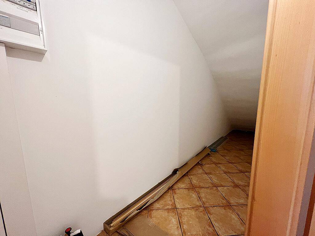 Praktischer Abstellraum unter einer Dachschräge mit gefliestem Boden für zusätzlichen Stauraum.