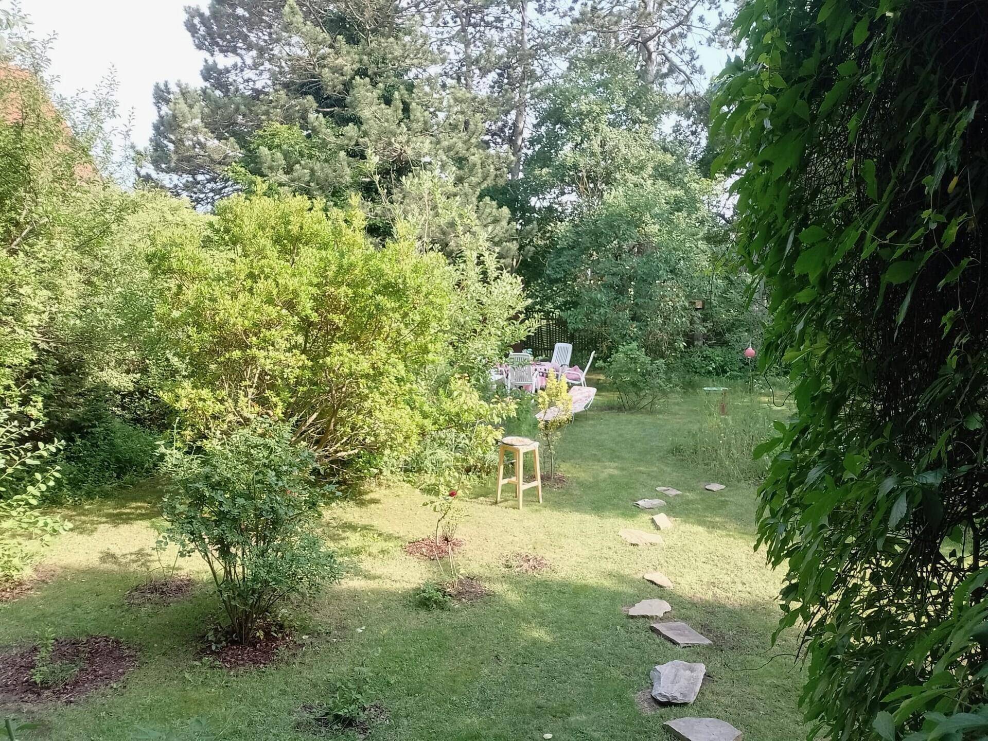 Weitläufiger Garten mit Rasenfläche und einer kleinen Sitzecke im Hintergrund.