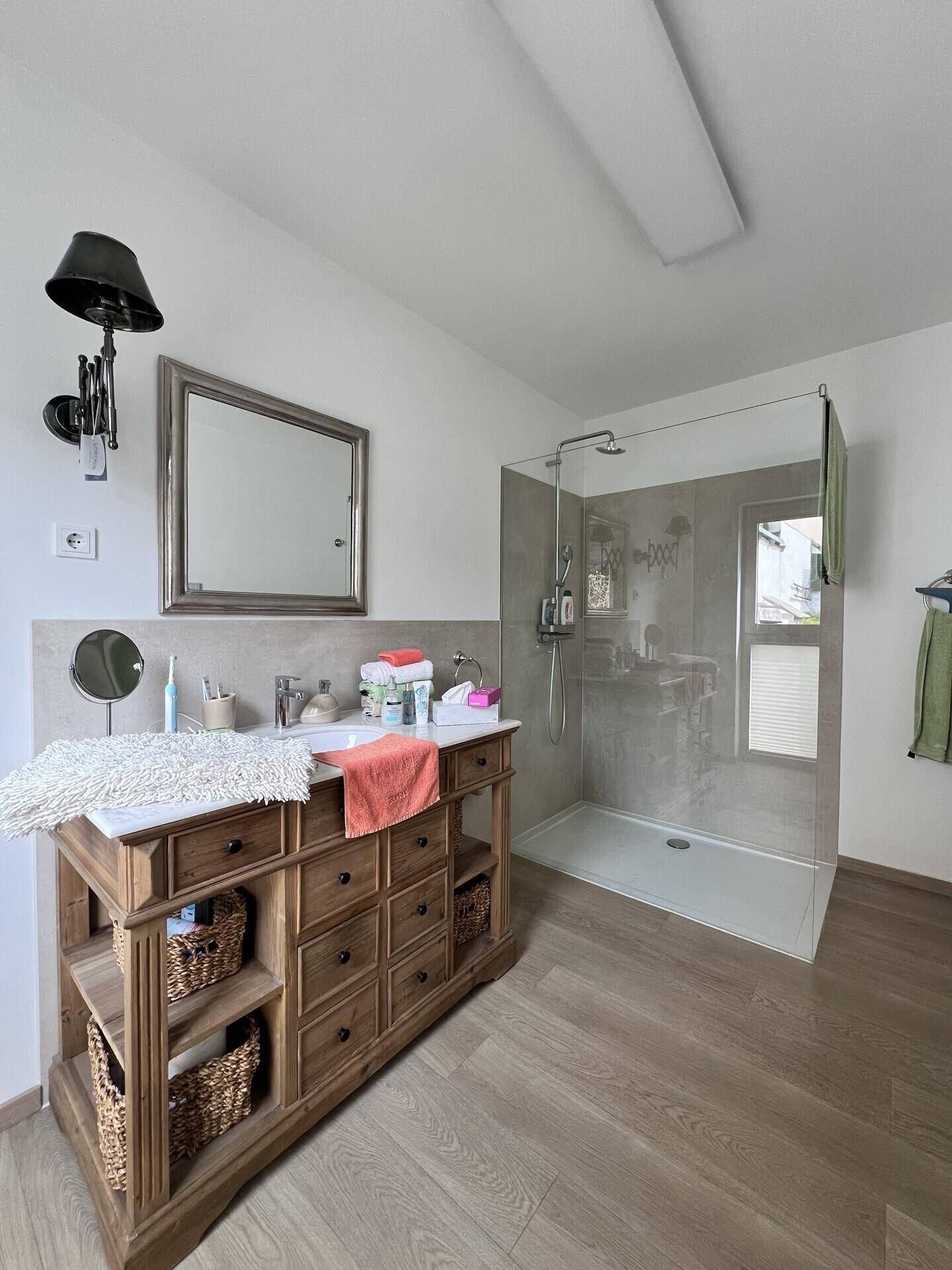 Modernes Badezimmer mit begehbarer Dusche, stilvollem Waschtisch und Holzoptikboden.