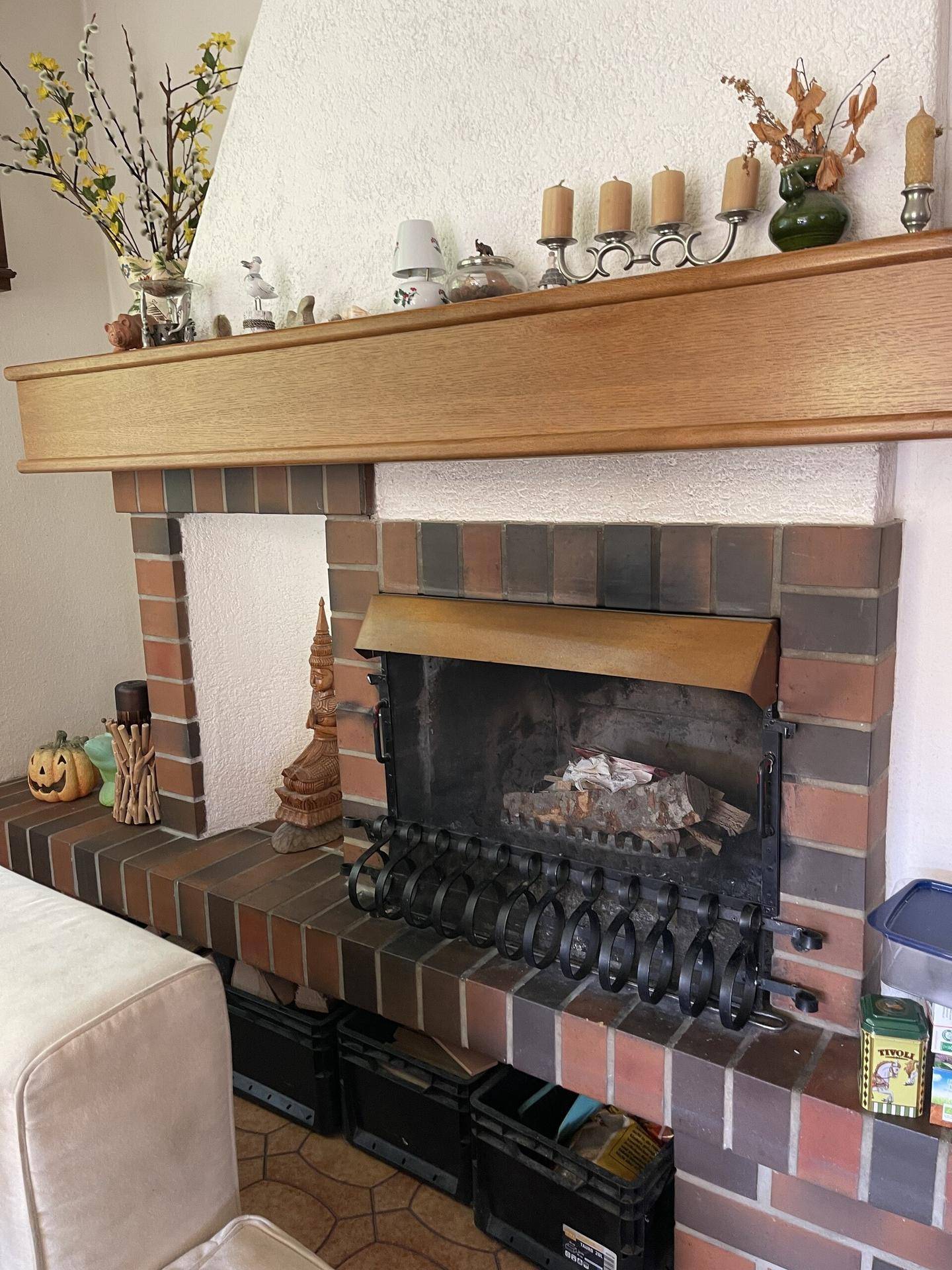 Rustikaler gemauerter Kamin mit Holzbalken und Dekoration im Wohnzimmer.