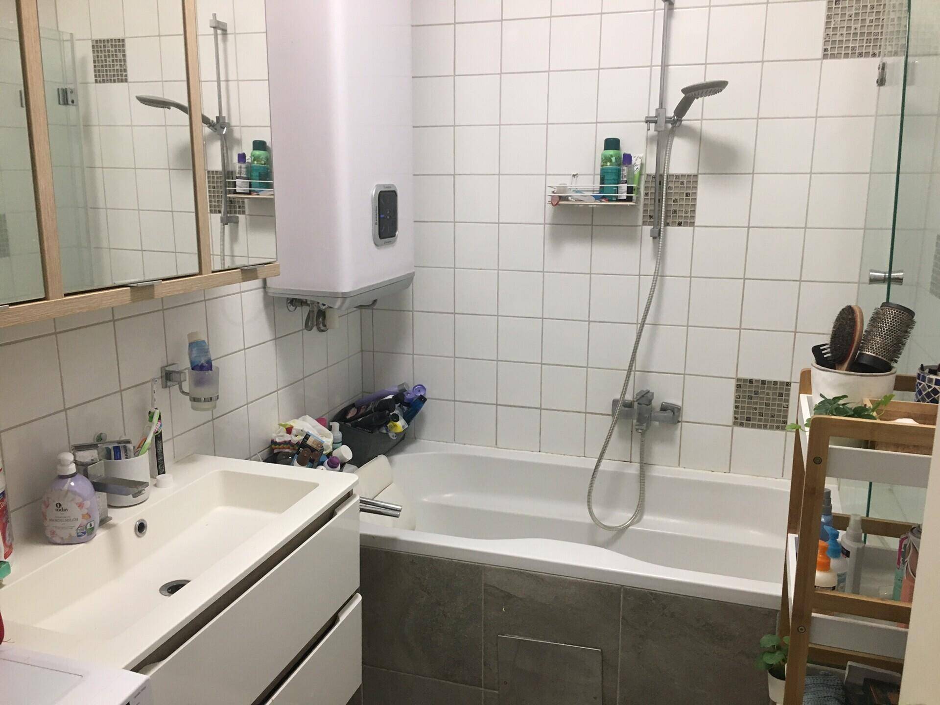 Helles Badezimmer mit Badewanne, Waschbecken und weißen Fliesen.