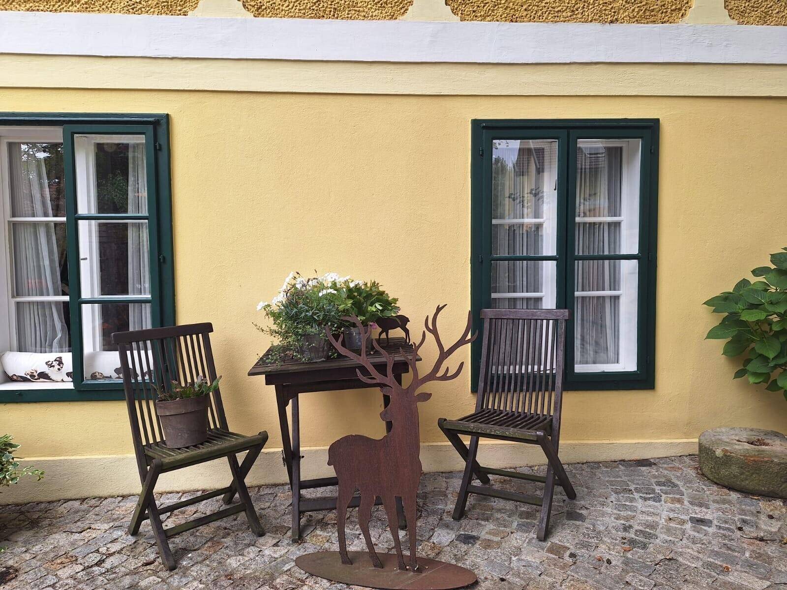 Gemütlicher Außenbereich im Innenhof mit Holzsitzgelegenheiten und dekorativem Hirsch.