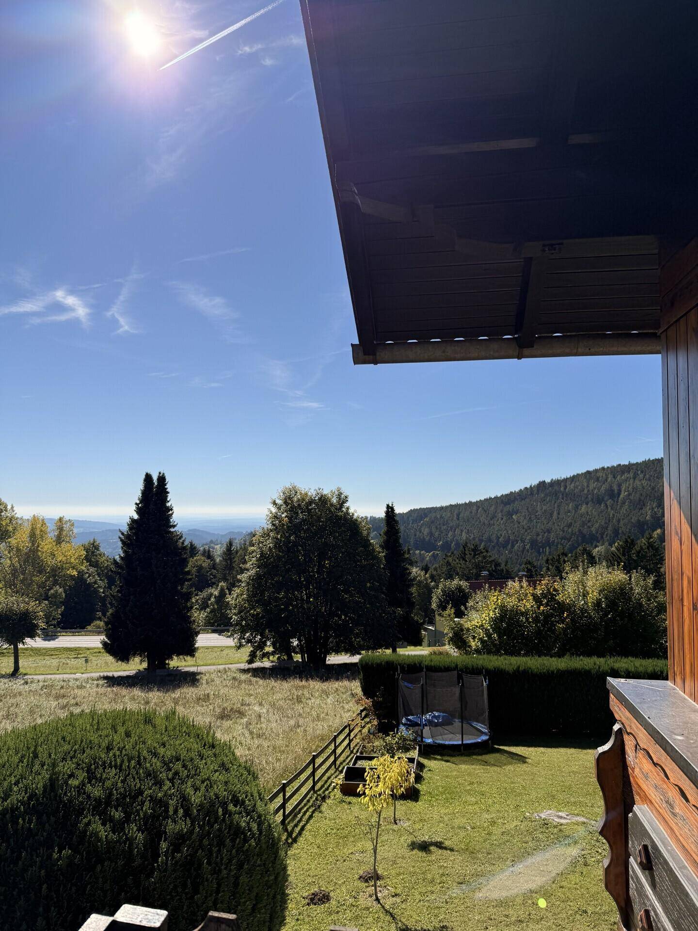 Balkon mit Holzelementen und weitem Ausblick auf die umliegende grüne Naturlandschaft.