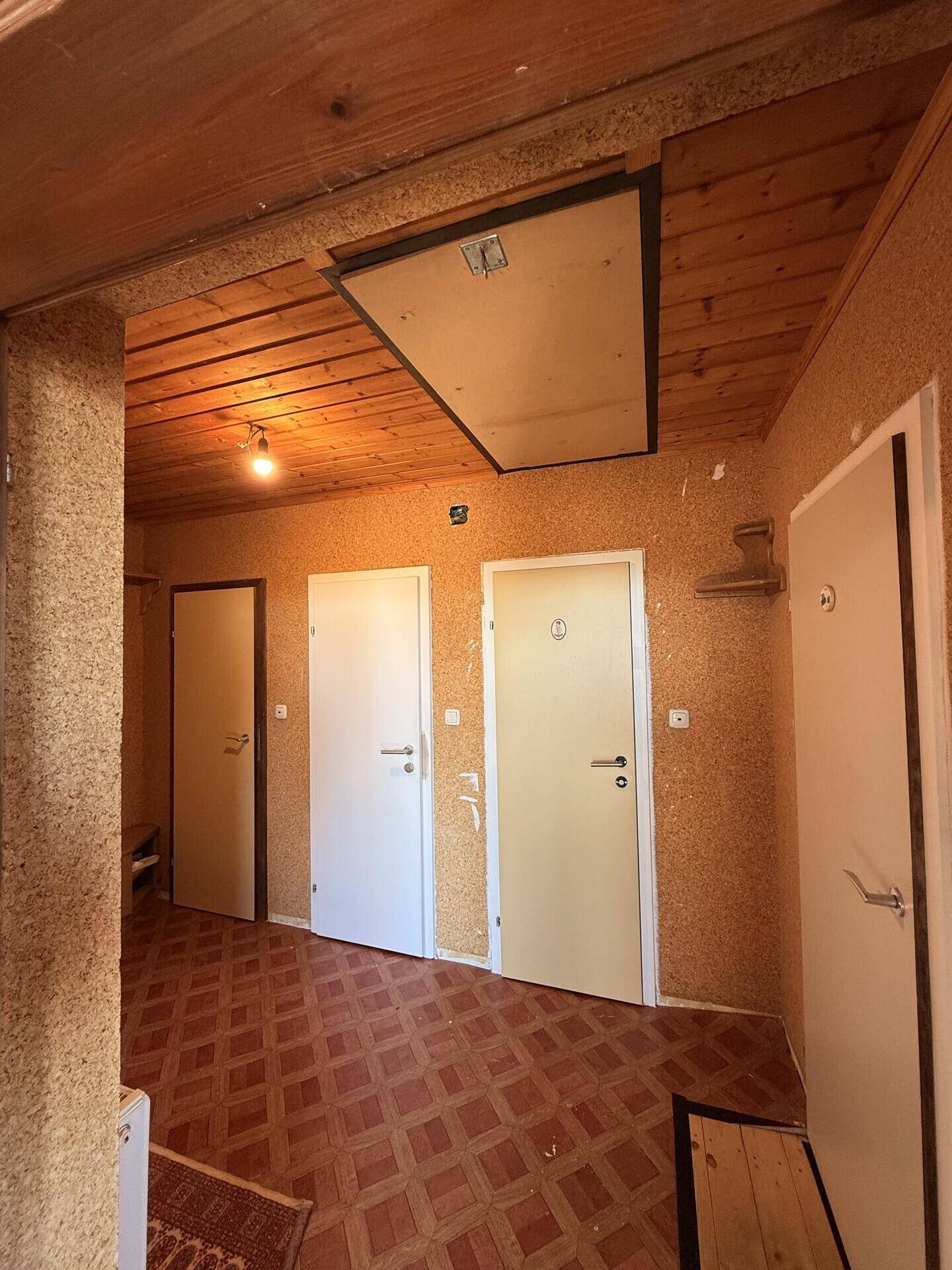 Rustikaler Flur mit Holzbalkendecke, Korktapete und mehreren Türen.