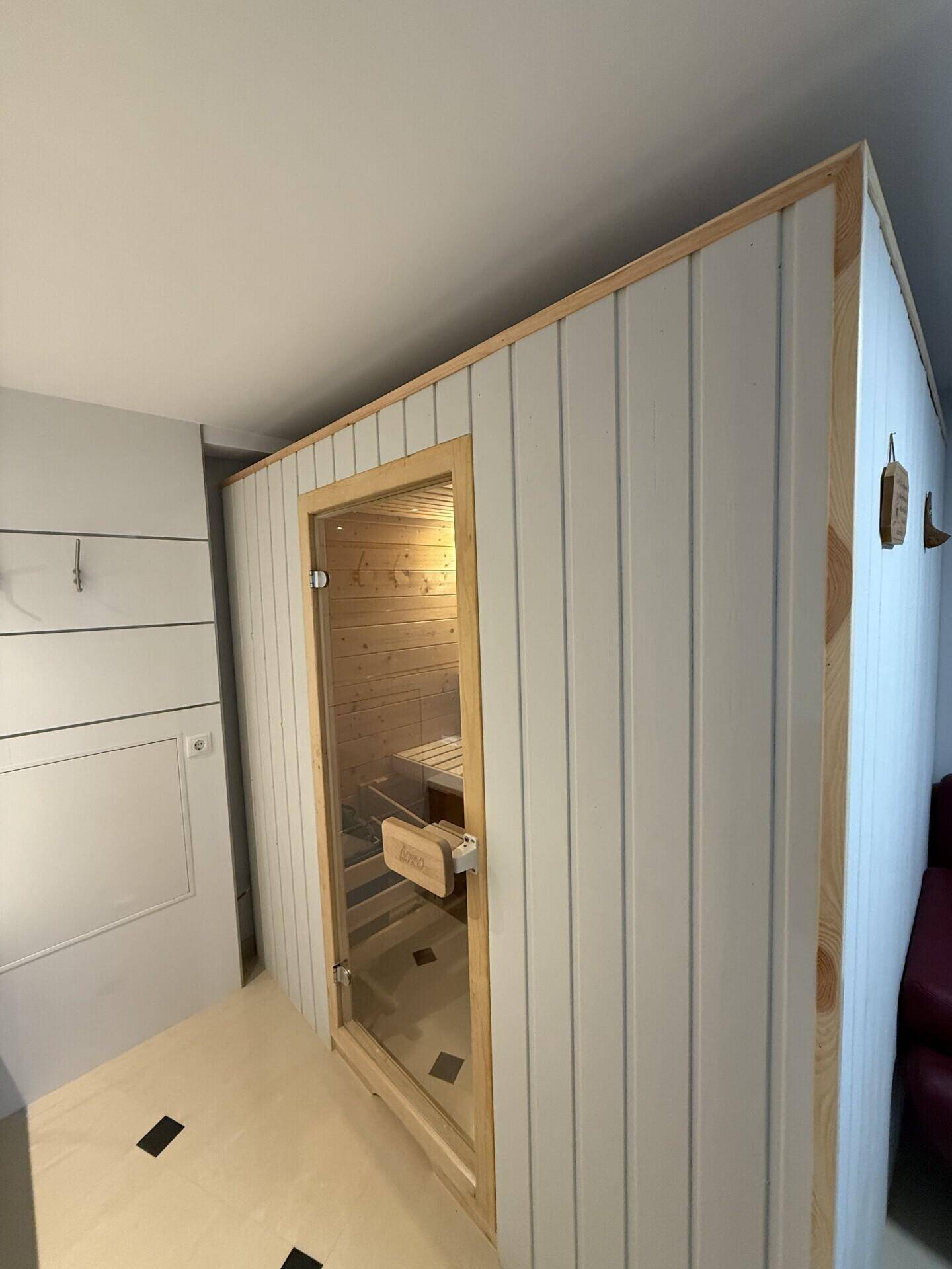Blick auf die moderne Sauna mit Holztür und Glasfront, integriert in den Innenbereich.