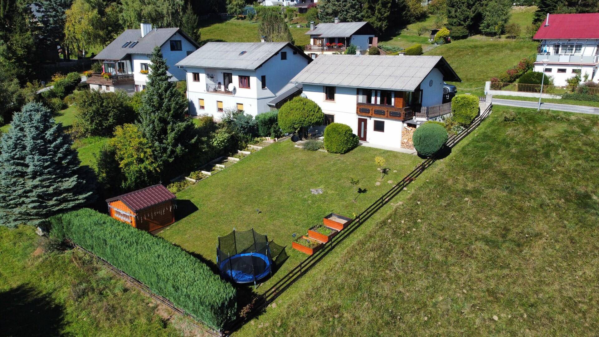 Weitläufiger Gartenbereich mit Trampolin und Gartenhaus, umgeben von weiteren Wohnhäusern.