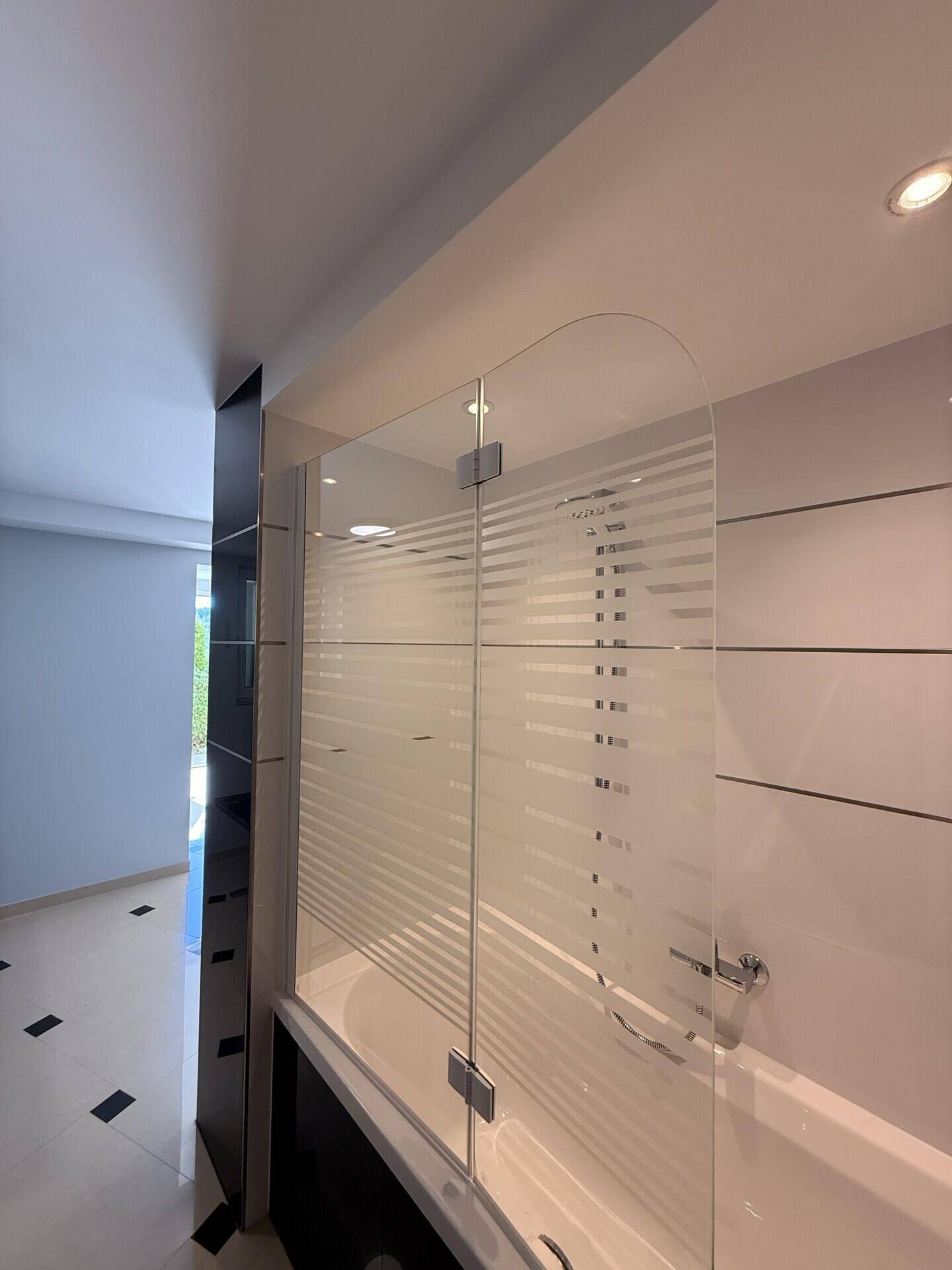 Helles Badezimmer mit Badewanne und eleganter Glasduschwand für modernen Komfort.