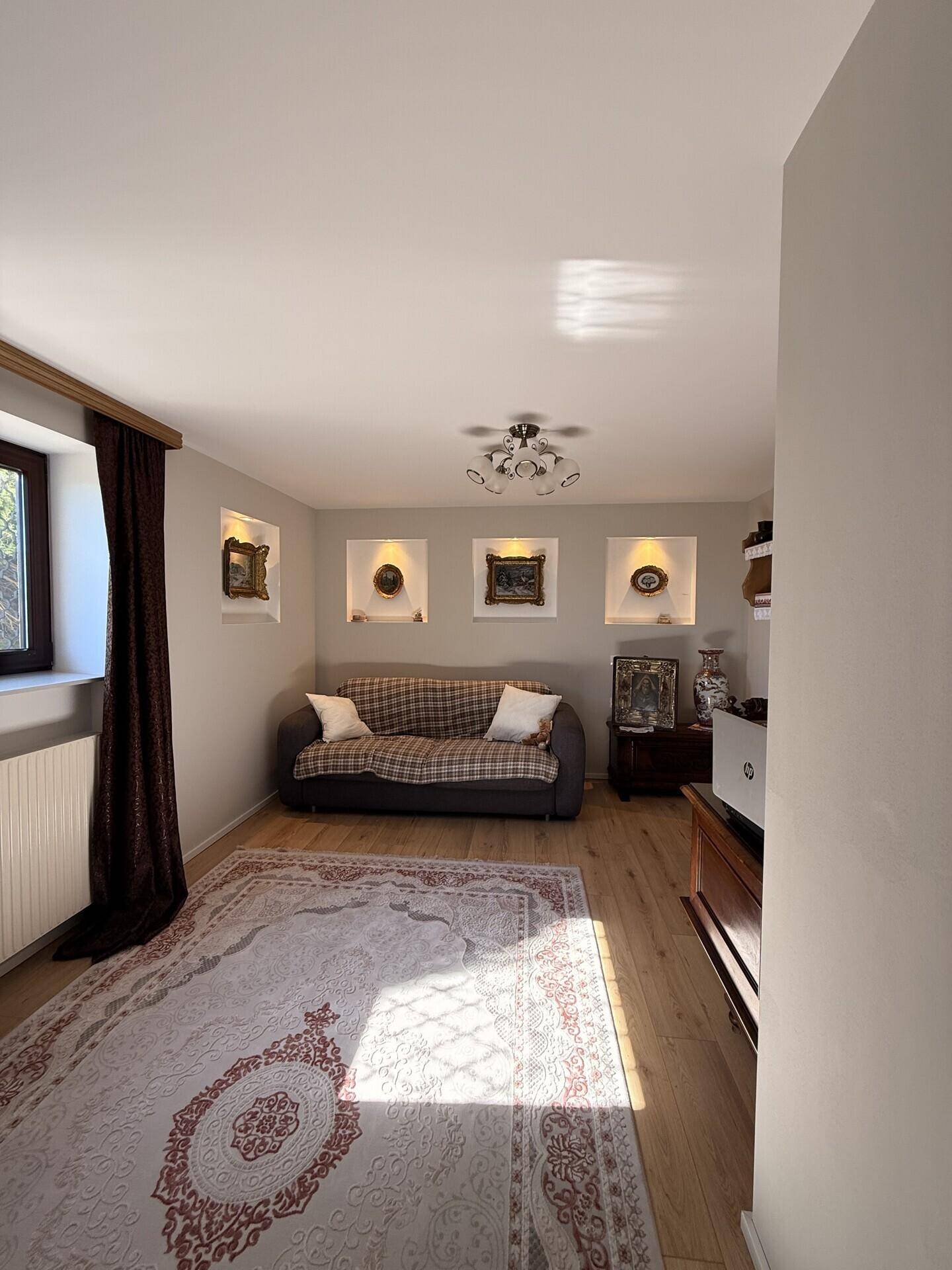Helles Wohnzimmer mit bequemer Couch, Fenster und beleuchteten Wandnischen.