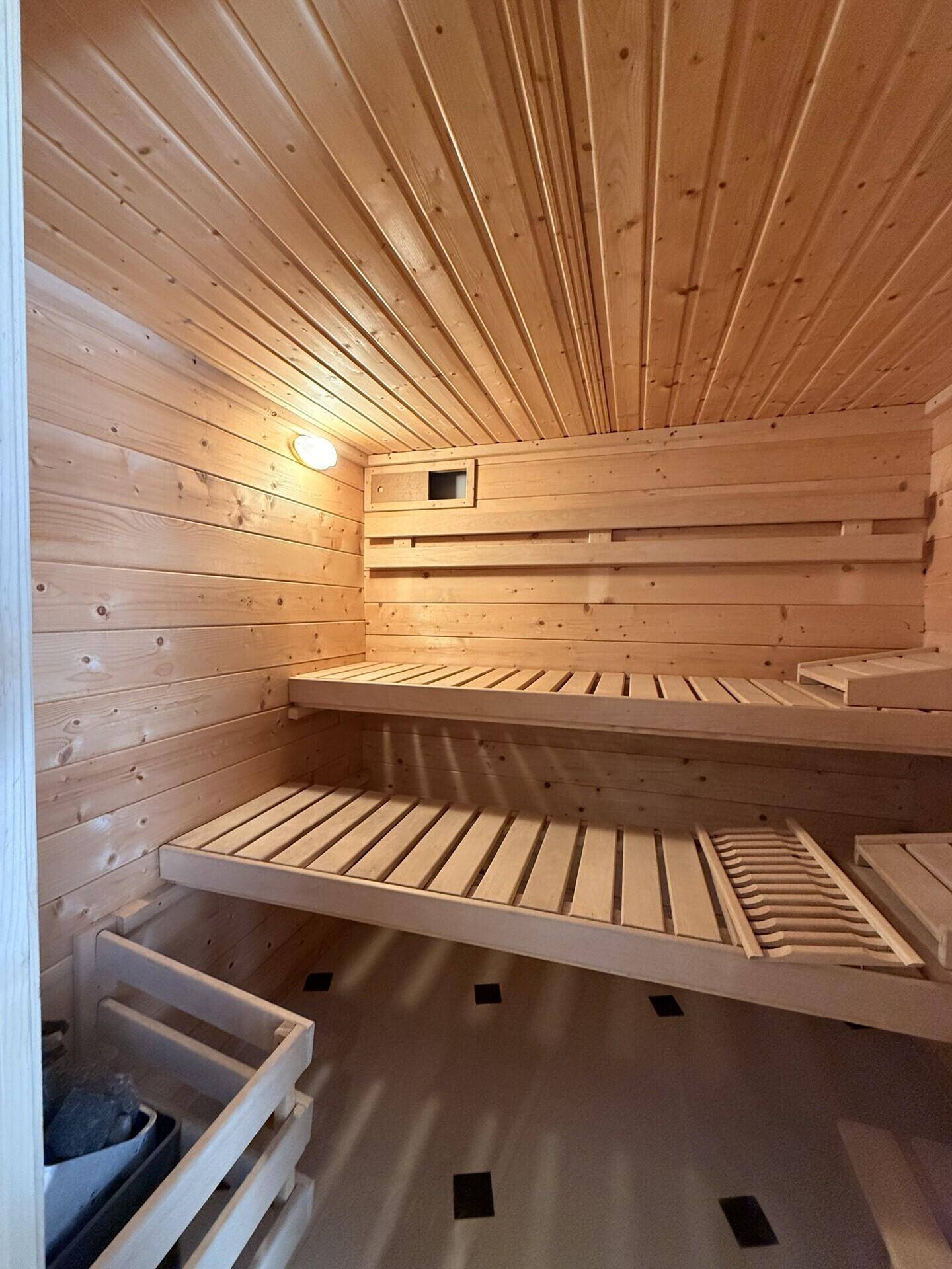 Gemütliche Holzsauna mit Sitzbänken und sichtbarem Saunaofen für entspannende Momente.
