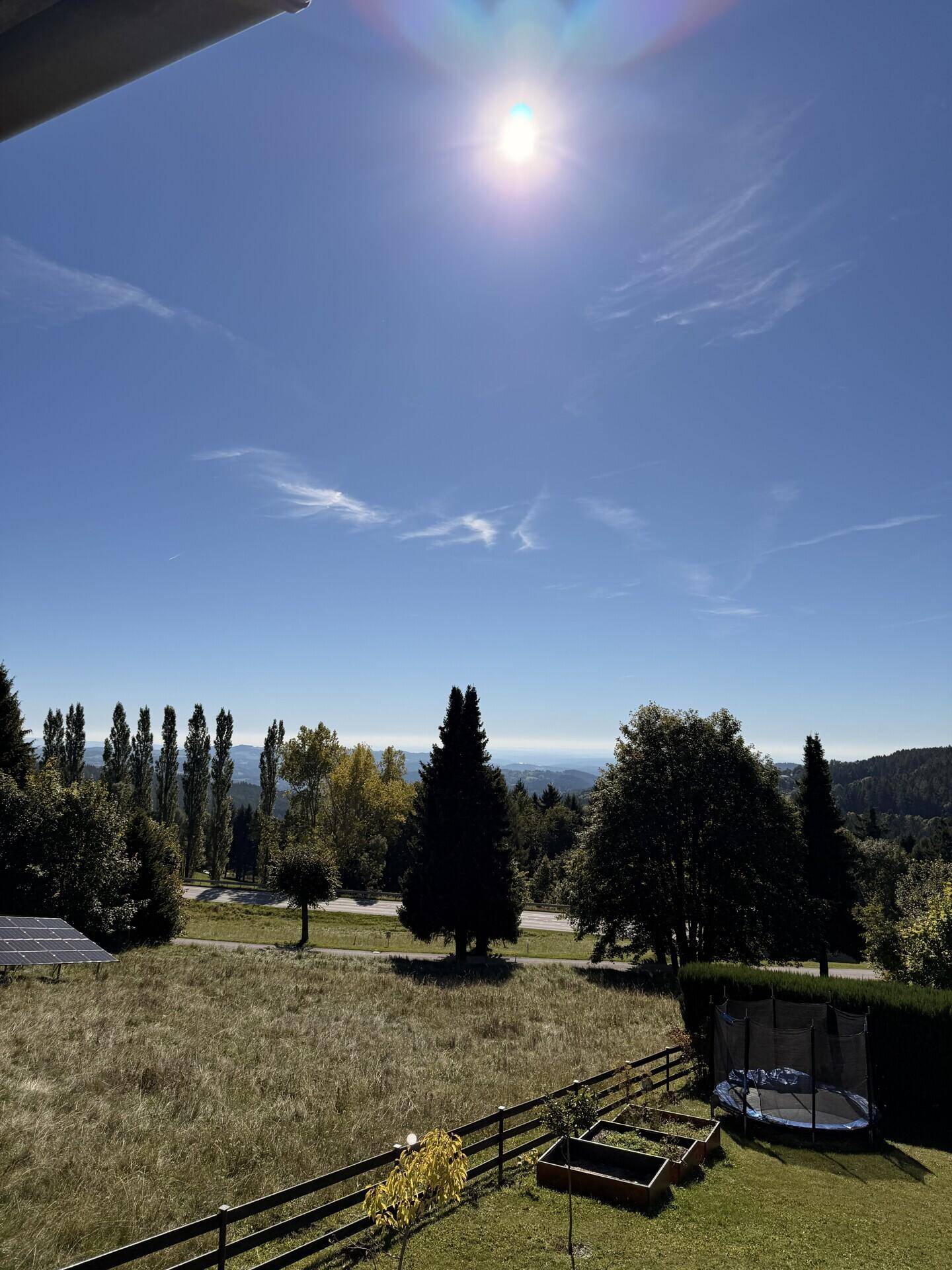Sonniger Garten mit Trampolin und weitem Blick über die Landschaft.