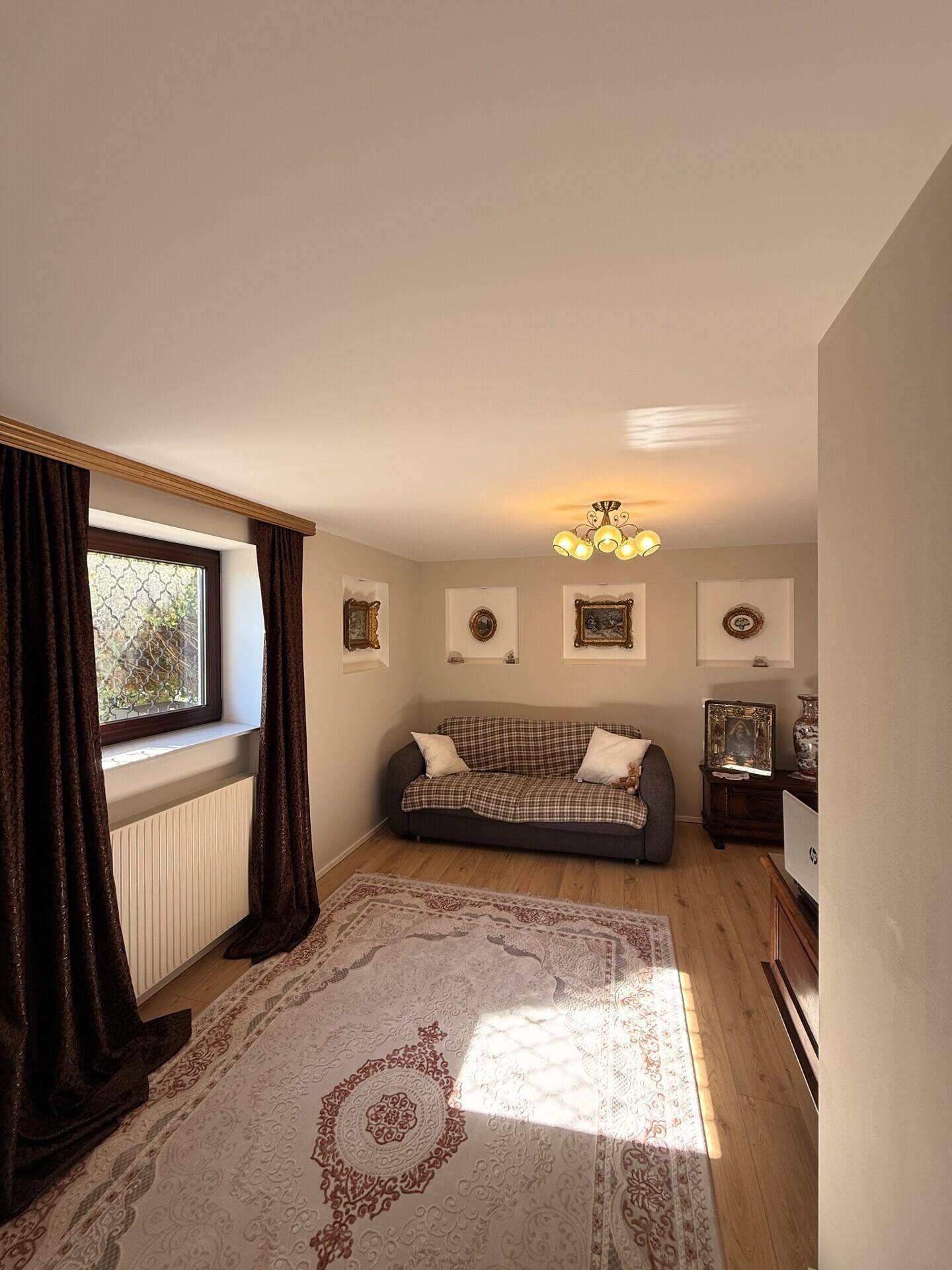 Gemütliches Wohnzimmer mit Sofa, Fenster und dekorativen Wandnischen.