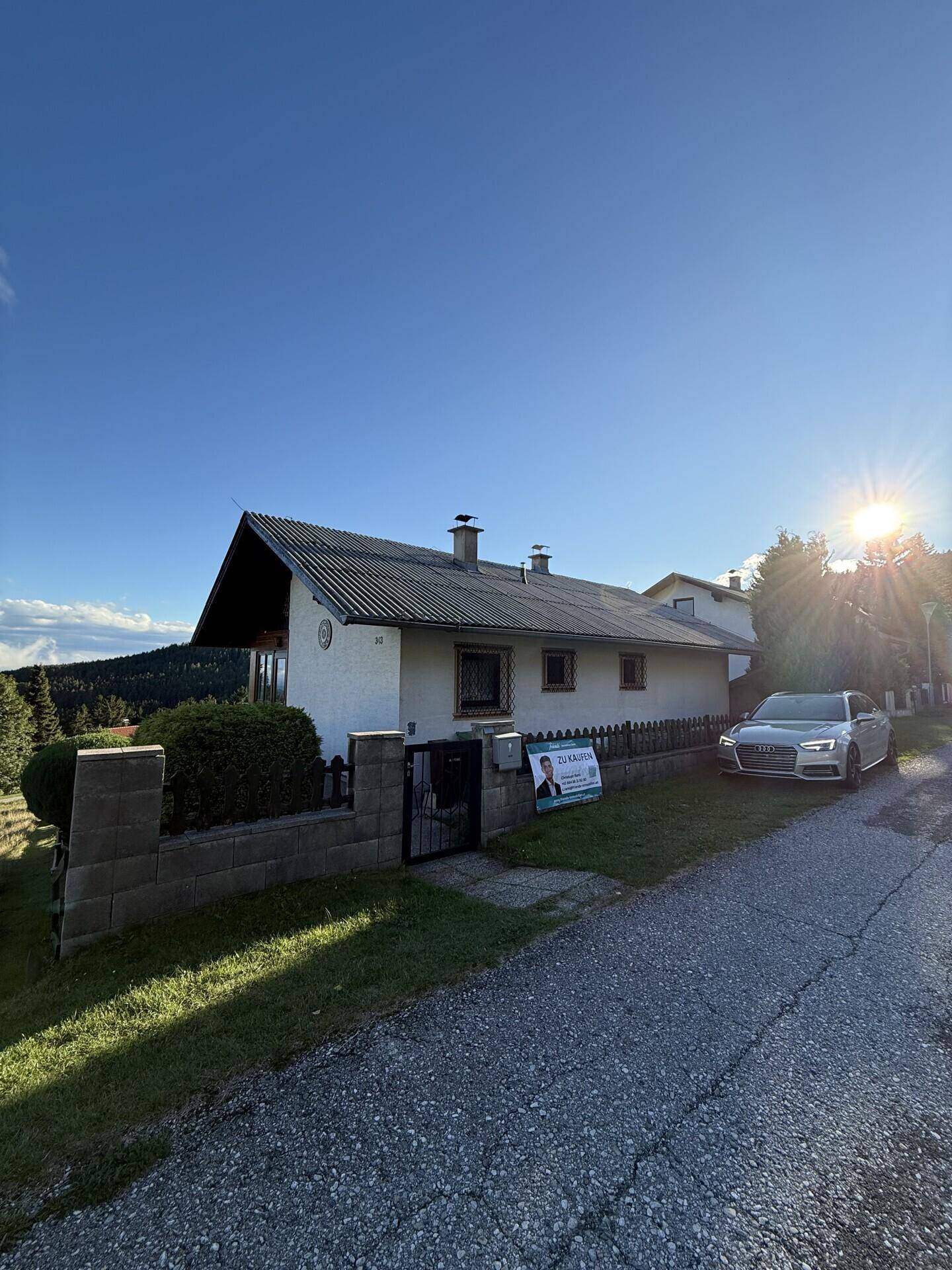 Einfamilienhaus mit Satteldach, Vorgarten und einem Auto auf der Einfahrt.