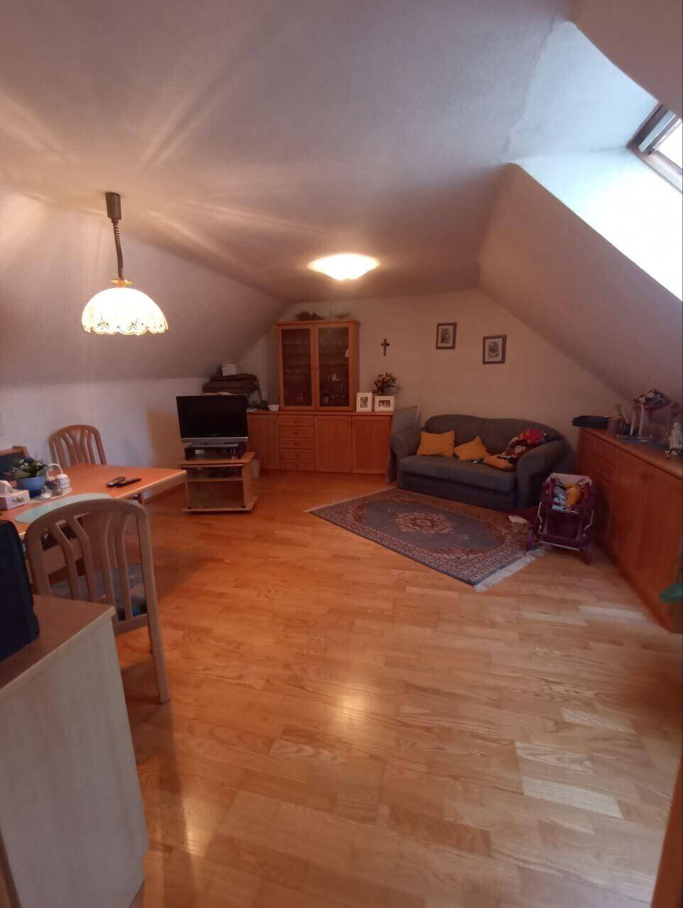 Gemütlicher Wohn-Essbereich im Dachgeschoss mit Holzboden und Dachfenster.