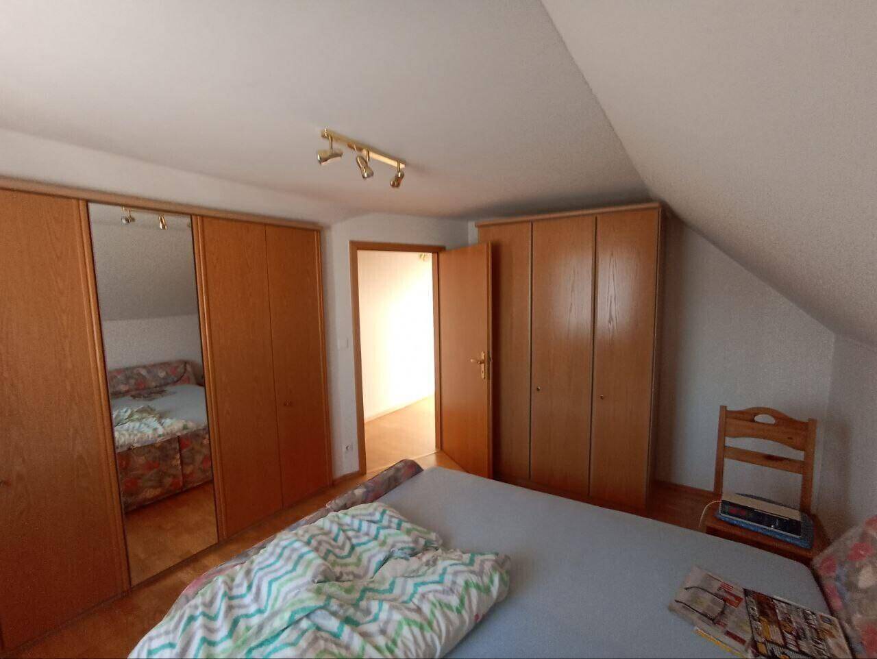 Schlafzimmer im Dachgeschoss mit schräger Decke und praktischen Einbauschränken.