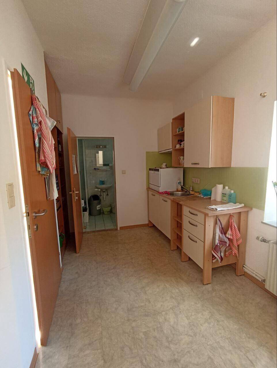 Kleine Küche mit Spülbecken, Arbeitsfläche und Zugang zu einem weiteren Raum.