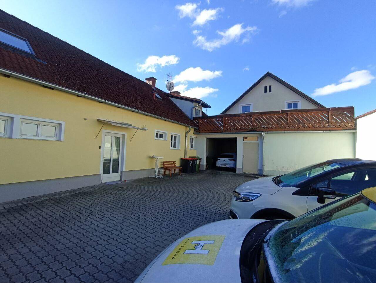 Gepflasterter Hofbereich mit parkenden Autos und Zugang zu einer Garage oder einem Carport.
